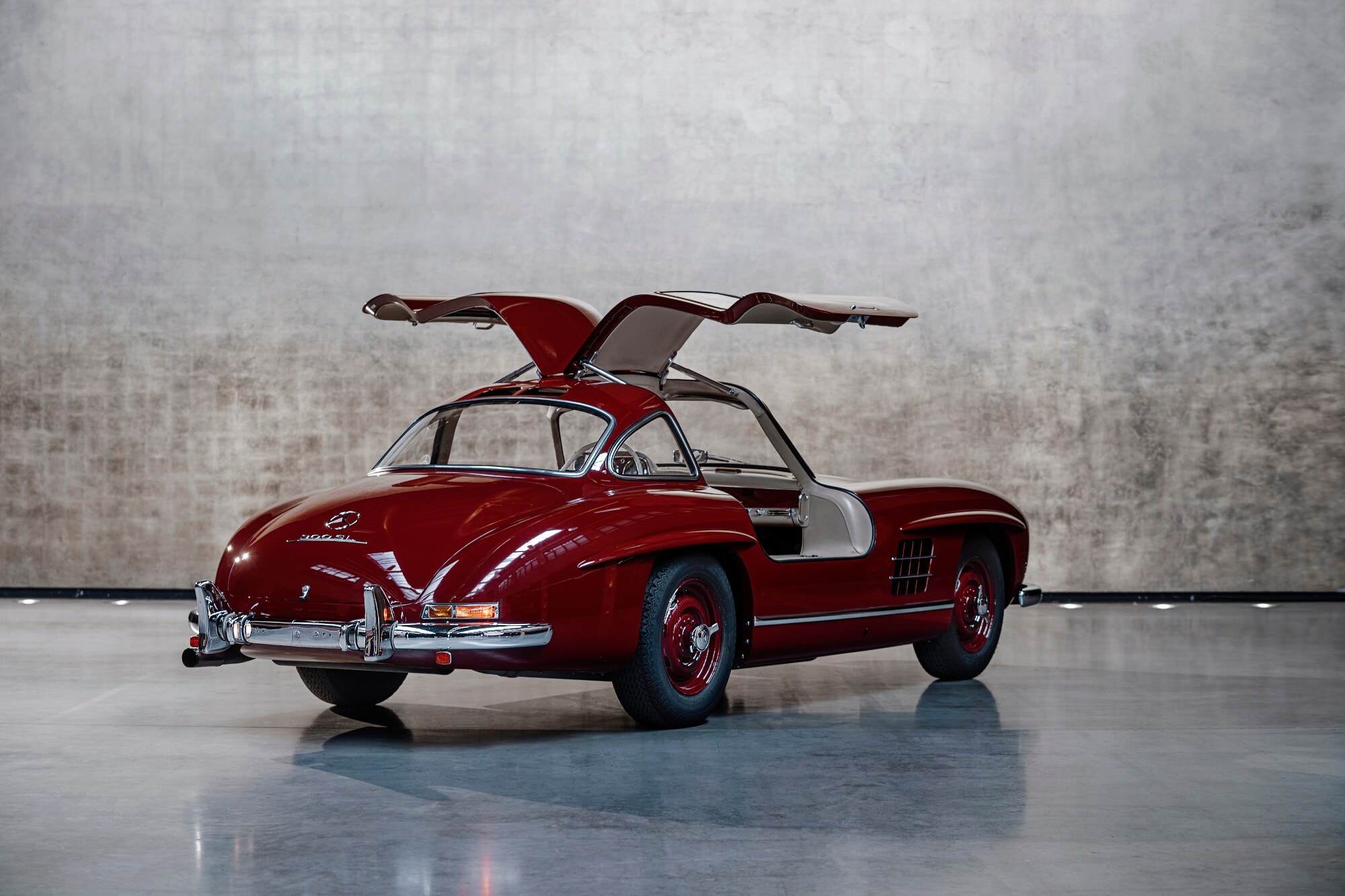 Ein dunkelroter Mercedes 300 SL mit geöffneten Möwenflügel-Türen im Studio Ein dunkelroter Mercedes 300 SL mit geöffneten Möwenflügel-Türen im Studio