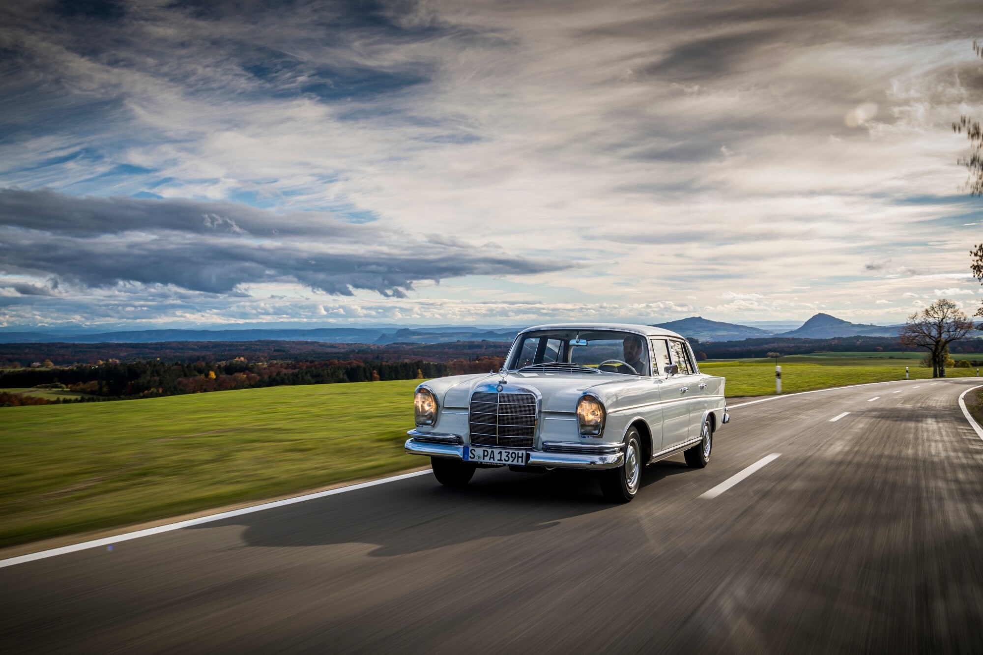Ein weißer Mercedes der Baureihe W 111 auf einer Landstraße Ein weißer Mercedes der Baureihe W 111 auf einer Landstraße