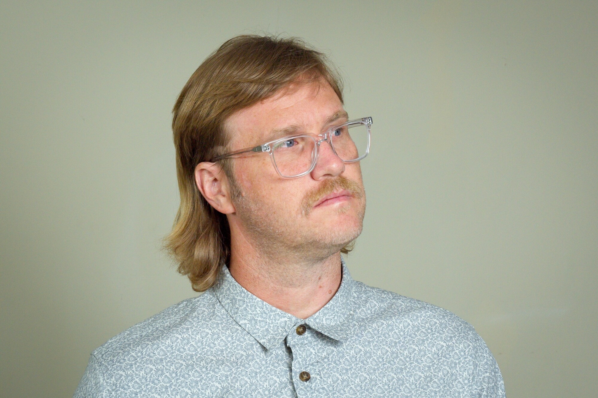 Ein Mann mit einem Mullet-Haarschnitt und Brille