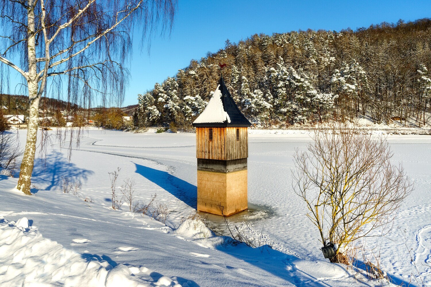 Eine Kirchturmspitze ragt aus dem zugefrorenen Wasser