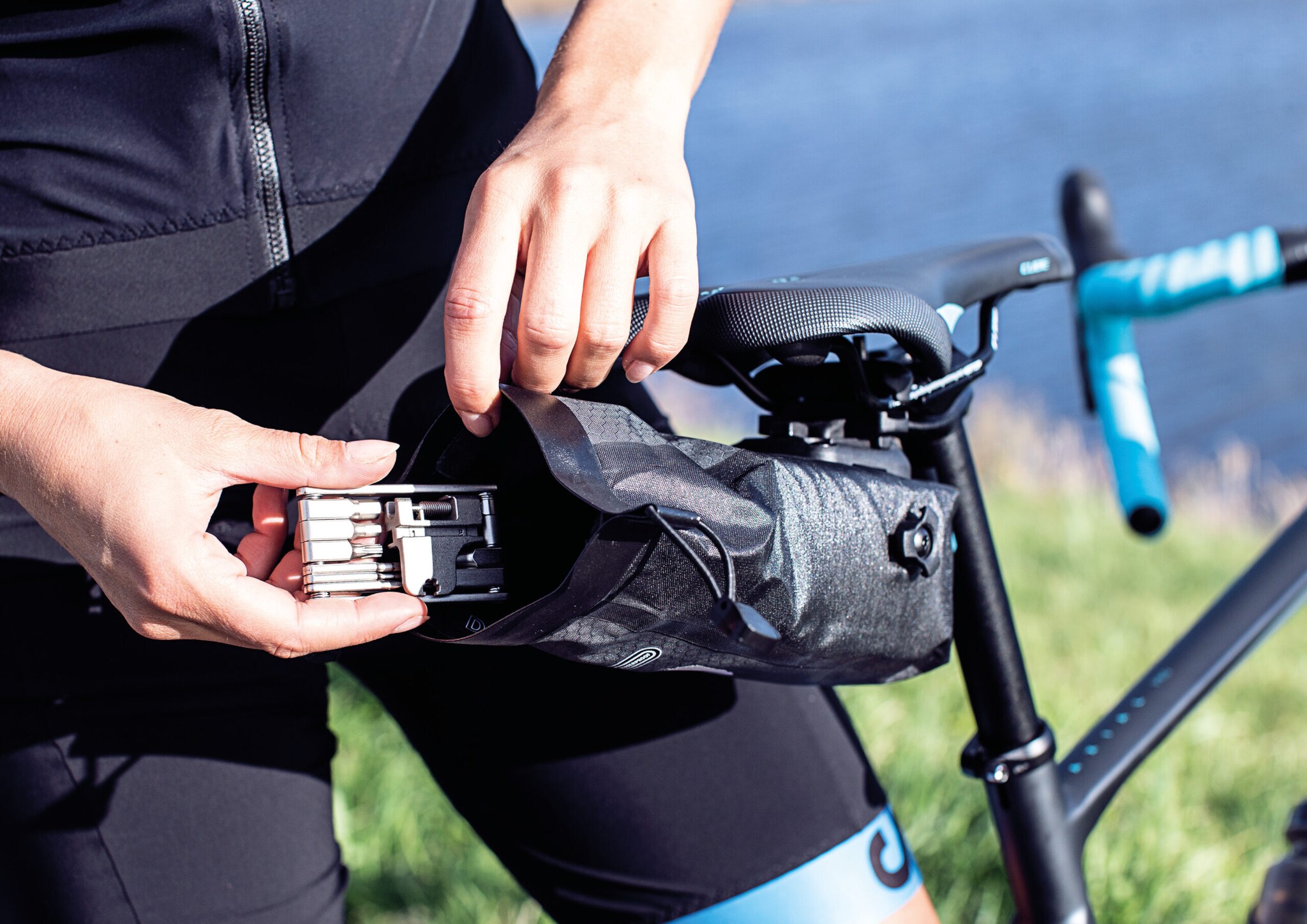 Ein Radfahrer legt ein Multitool-Werkzeug in seine Satteltasche