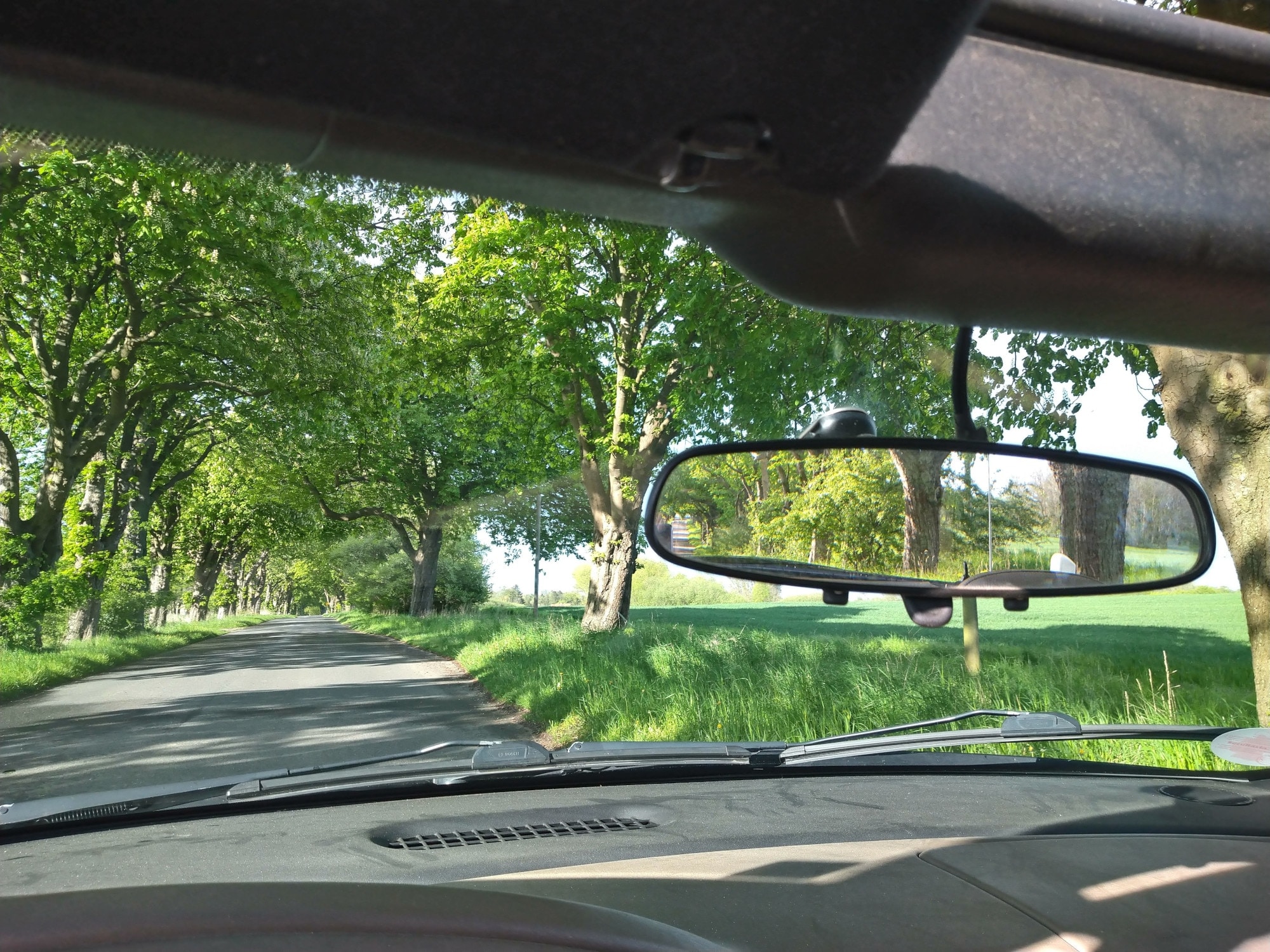 Blick durch die Frontscheibe eines Autos in die grüne Landschaft Blick durch die Frontscheibe eines Autos in die grüne Landschaft