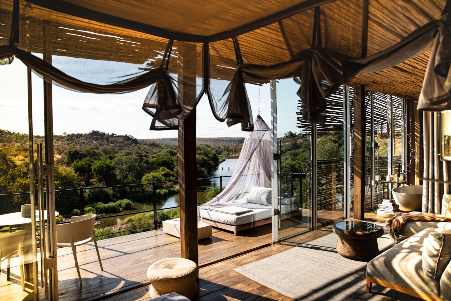 Ein luxuriös ausgestattetes Loft mit Strohdach und offener Fensterfront, die einen Panoramablick auf den Kruger Nationalpark gibt