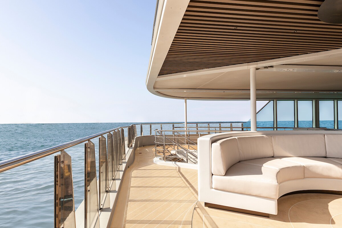 Loungebereich an Deck eines Schiffes mit großer heller Couch, im Hintergrund Meer