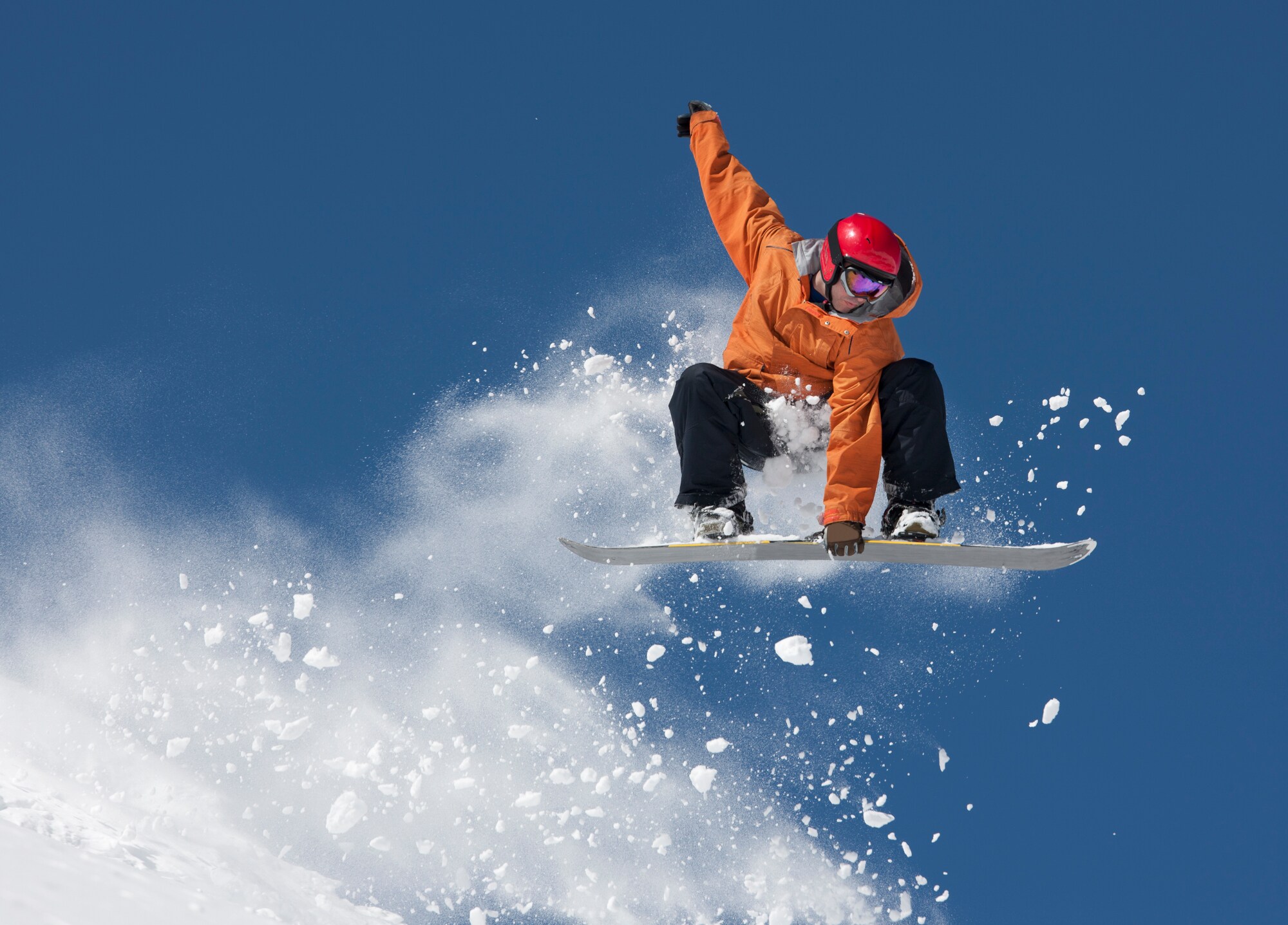 Ein Snowboarder hält sich an dem Board an seinen Füßen bei einem Sprung in der Luft fest Ein Snowboarder hält sich an dem Board an seinen Füßen bei einem Sprung in der Luft fest