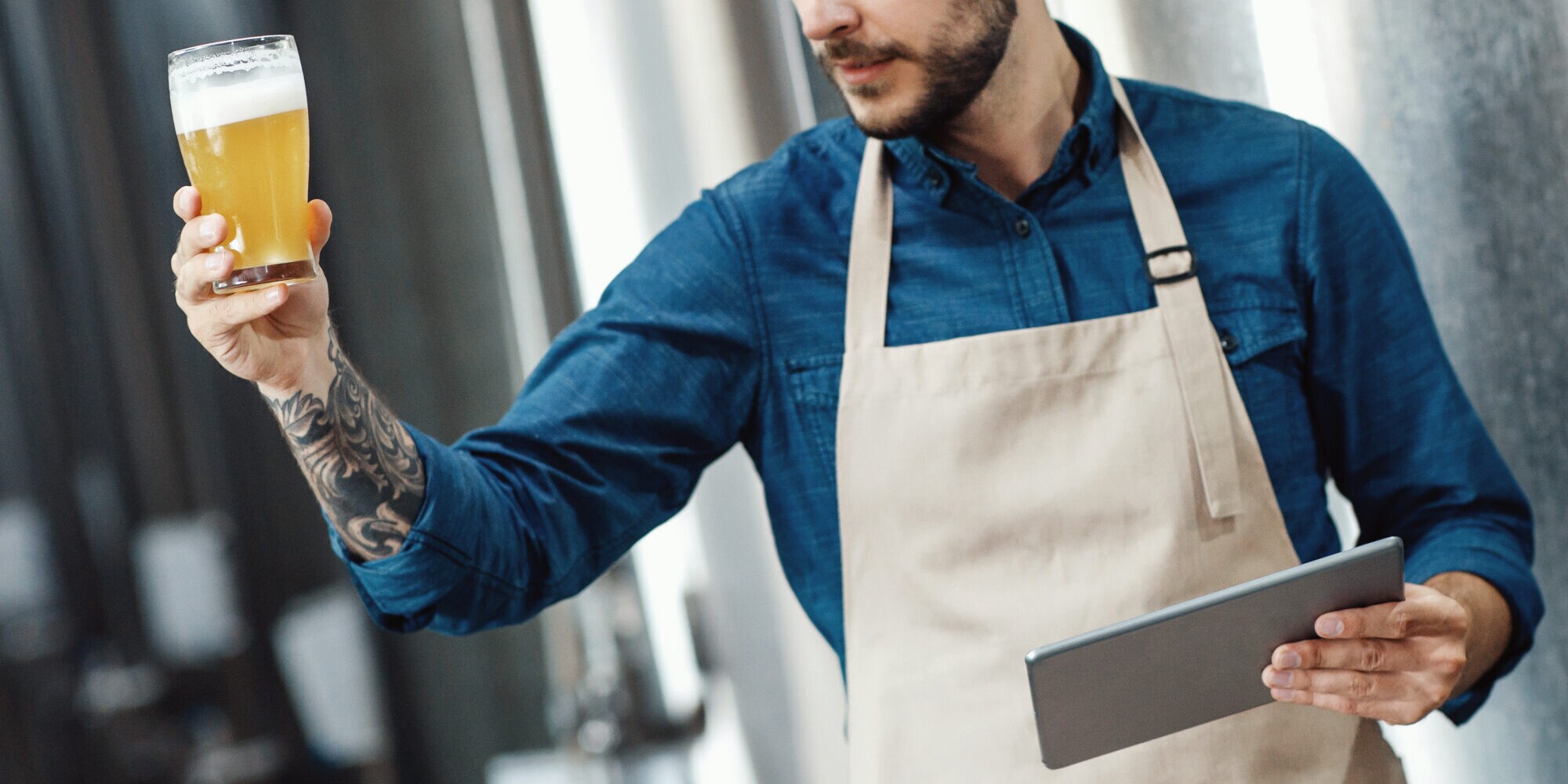 Ein Mann hält ein Bier in der Hand und schaut es prüfend an Ein Mann hält ein Bier in der Hand und schaut es prüfend an