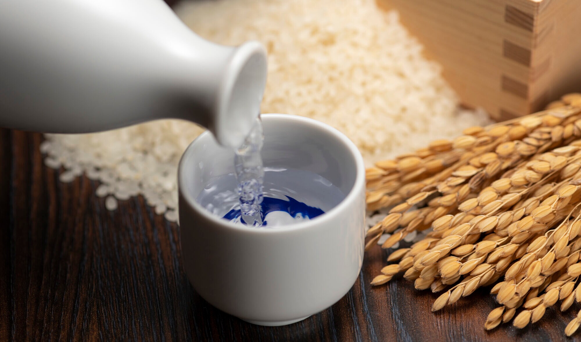 Reiswein wird in einen kleinen Porzellanbecher gefüllt Reiswein wird in einen kleinen Porzellanbecher gefüllt