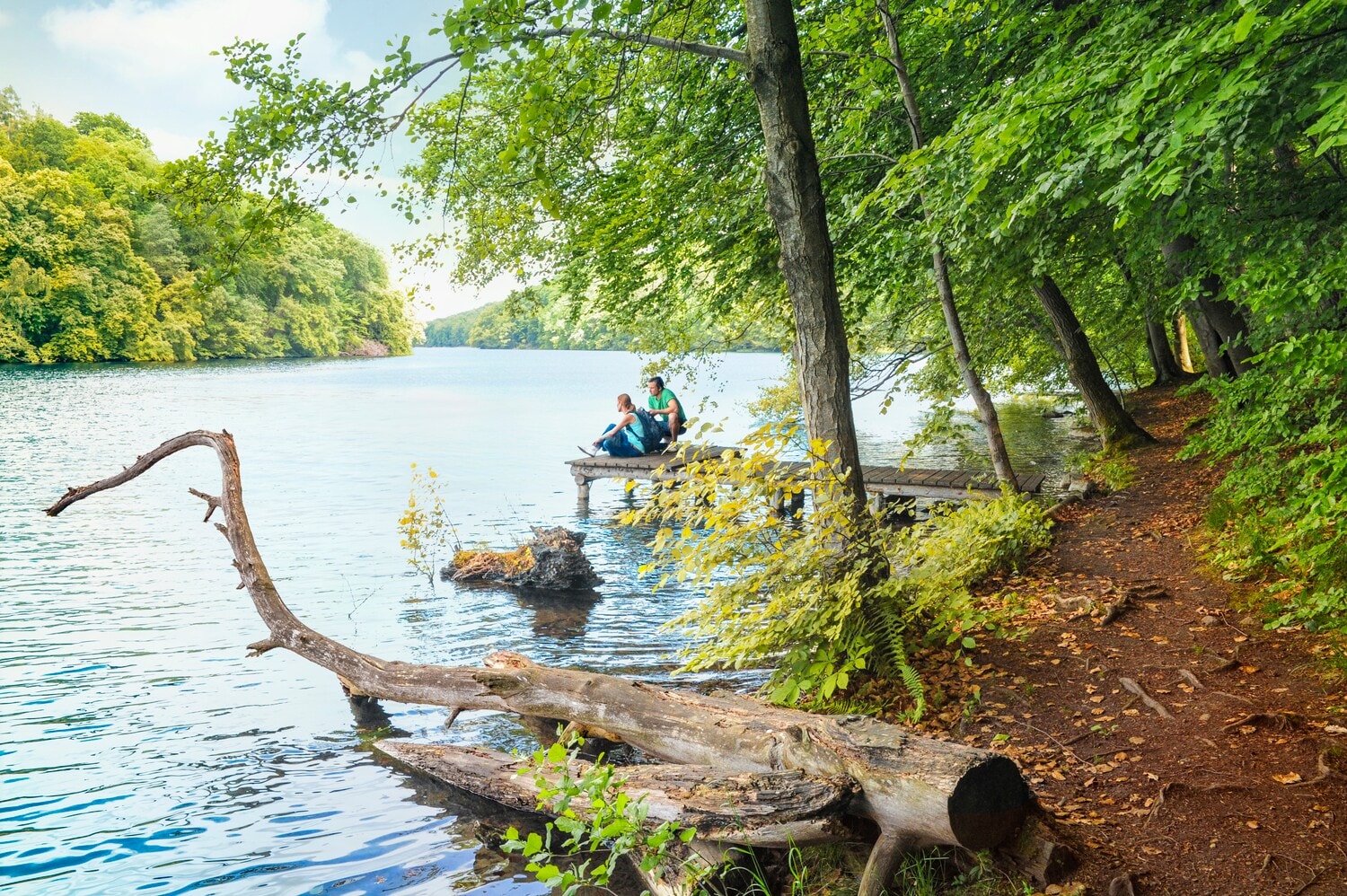 Ein junges Paar sitzt auf einem Steg am See Ein junges Paar sitzt auf einem Steg am See