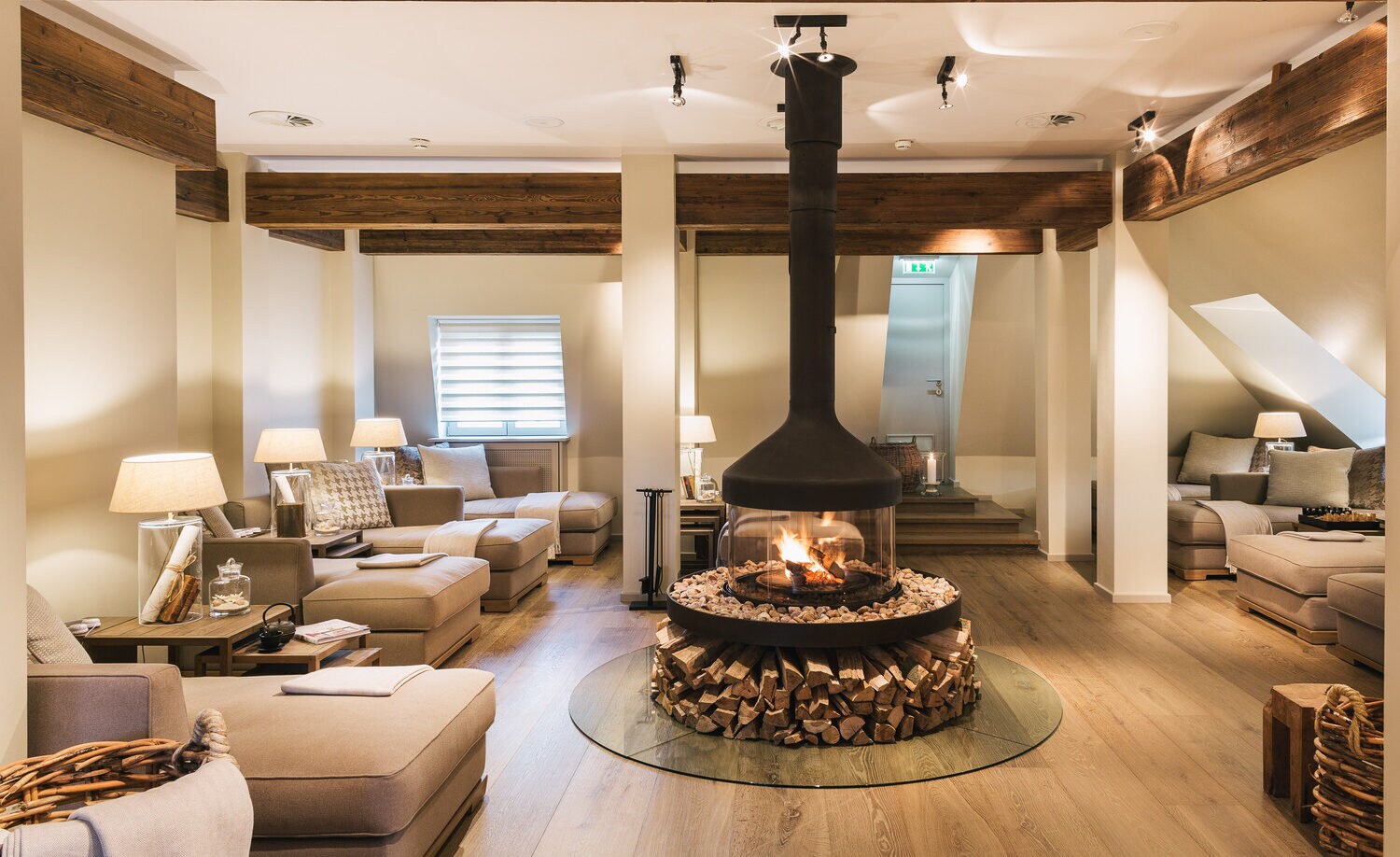 Um einen runden Glaskamin stehen helle Sofas.