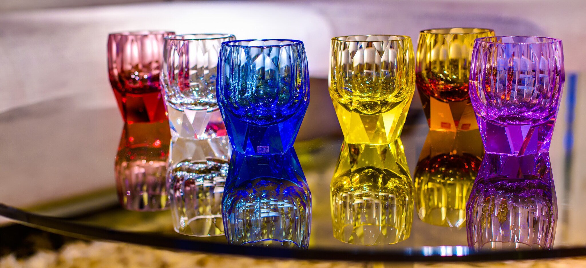 Zwei facettenreiche, handgeschliffene Whisky-Tumbler, davon ein Topazfarbener, auf einem Tisch mit zwei Limettenspalten