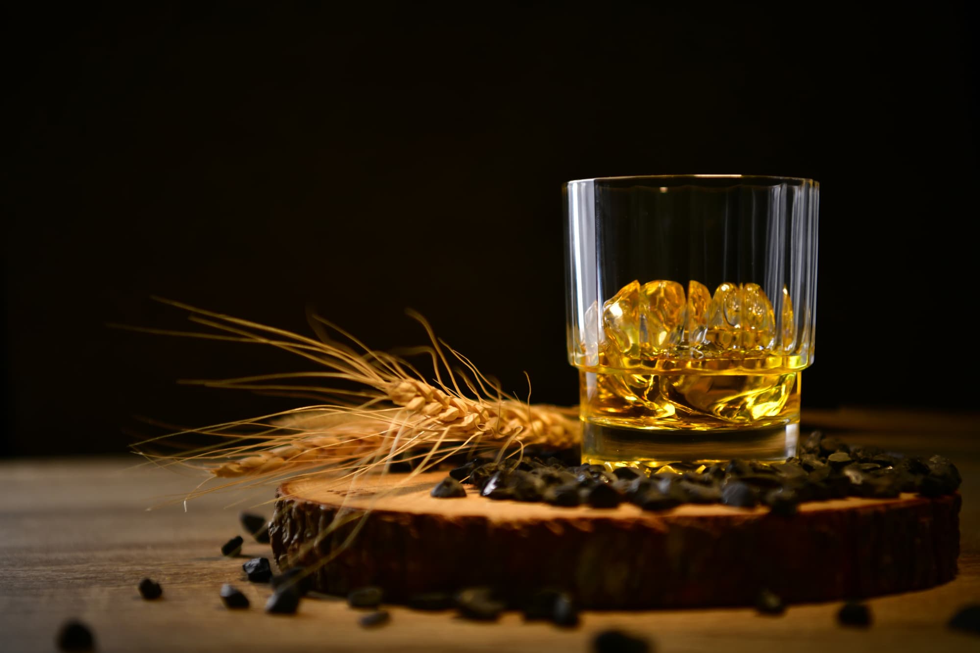 Ein Glas mit Whiskey, daneben Malz und Gerste