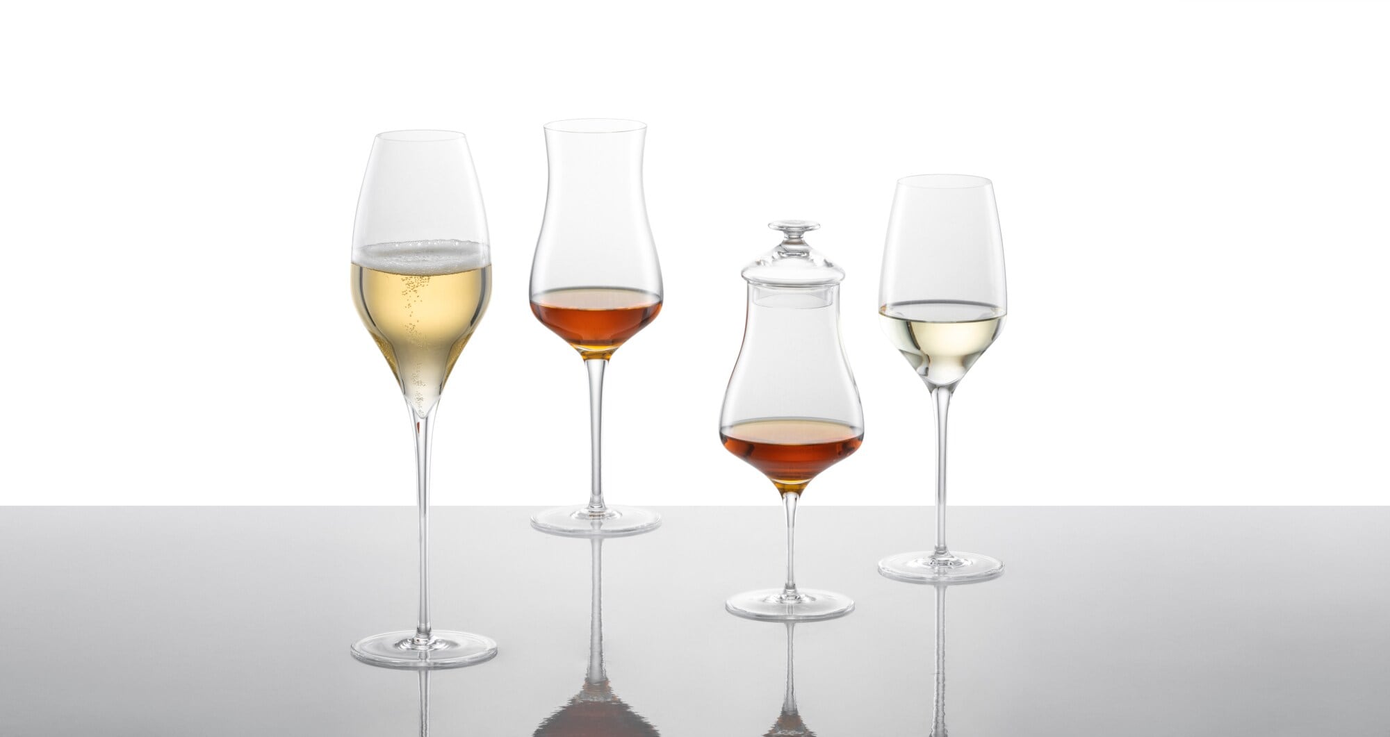 Zwei leicht gefüllte Verkostungsgläser, eins davon mit Deckel, sowie ein klassisches Weißweinglas von Zwiesel Glas stehen auf einer glatten, glänzenden Fläche Zwei leicht gefüllte Verkostungsgläser, eins davon mit Deckel, sowie ein klassisches Weißweinglas von Zwiesel Glas stehen auf einer glatten, glänzenden Fläche