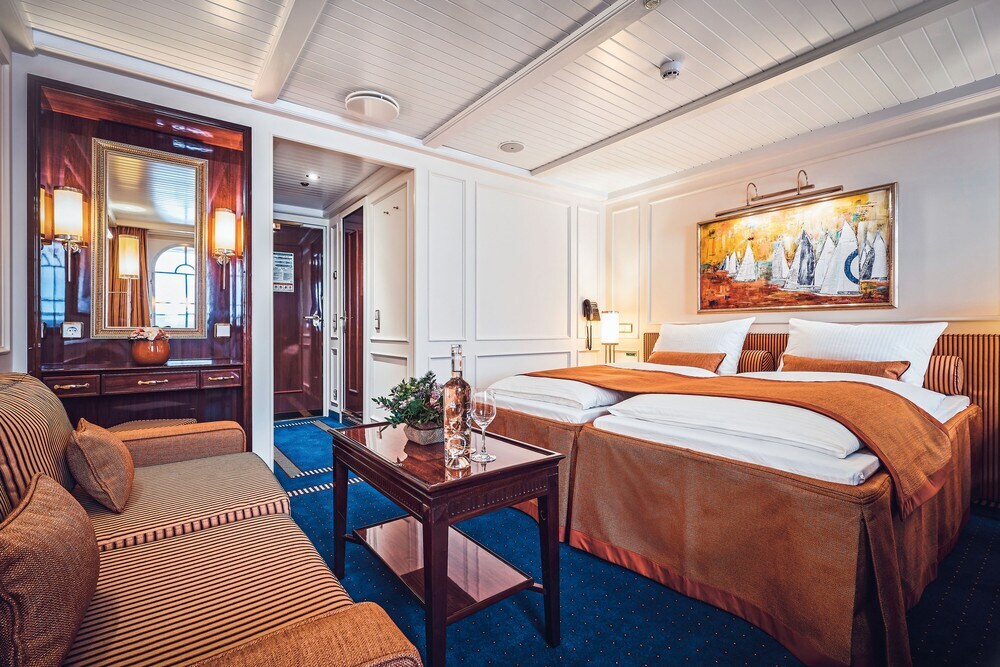 Elegante Schiffskabine mit großem Bett, edlem Holztisch und Couch