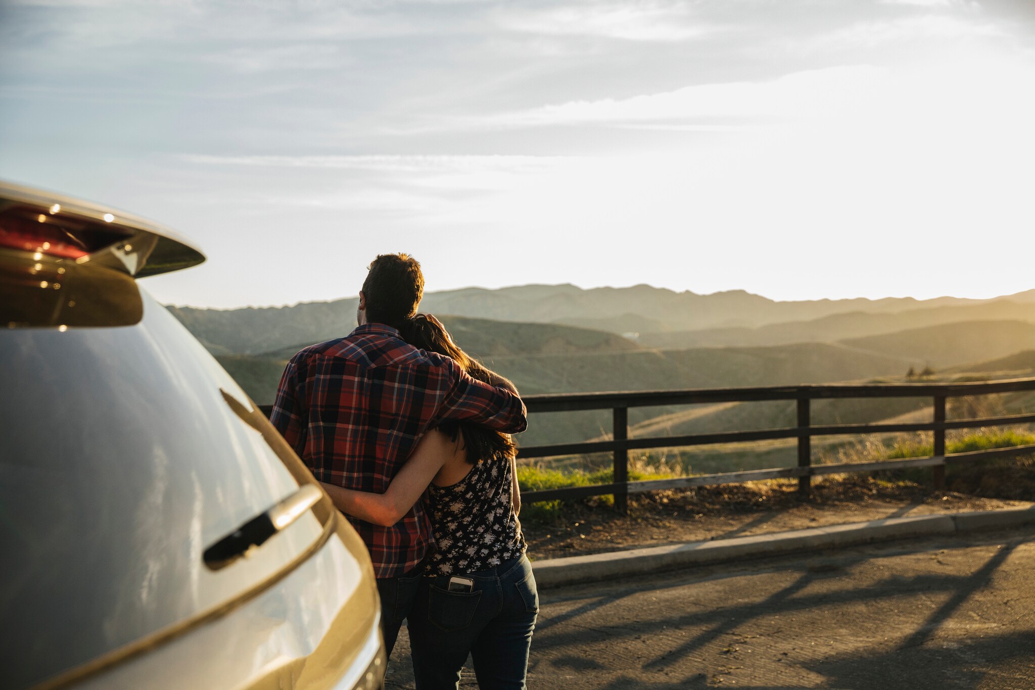 Ein Paar steht vor dem Auto und genießt die Aussicht über die Landschaft. Ein Paar steht vor dem Auto und genießt die Aussicht über die Landschaft.