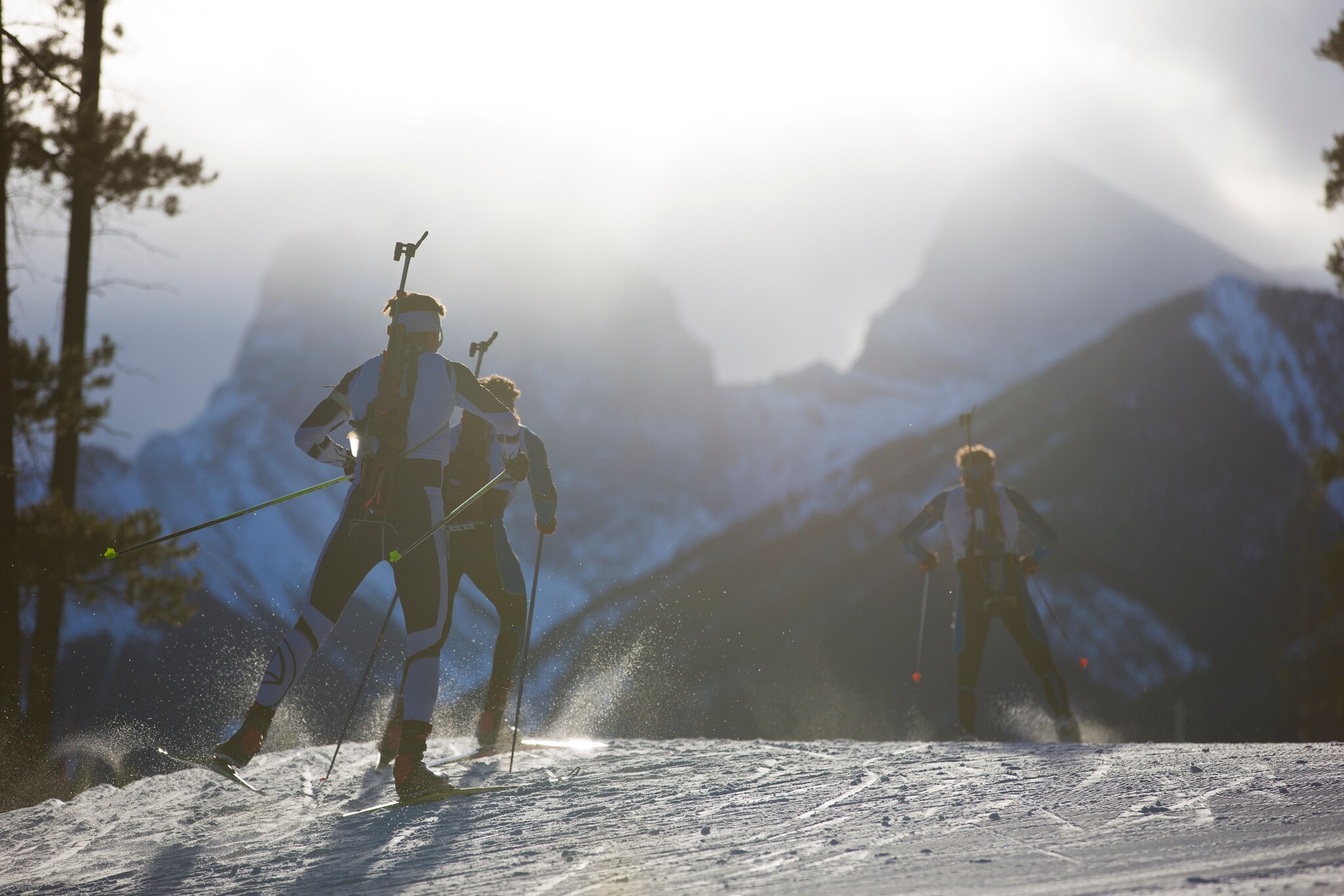 Drei Männer auf Skiern mit einem Biathlon-Gewehr auf dem Rücken fahren durch den Schnee. Drei Männer auf Skiern mit einem Biathlon-Gewehr auf dem Rücken fahren durch den Schnee.