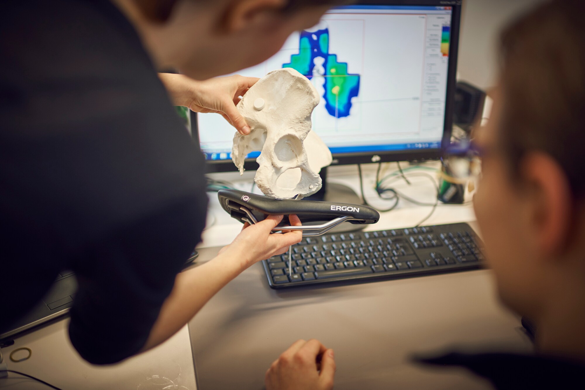 Ein Modell des menschlichen Beckens wird von einer Person an einen Fahrradsattel gehalten