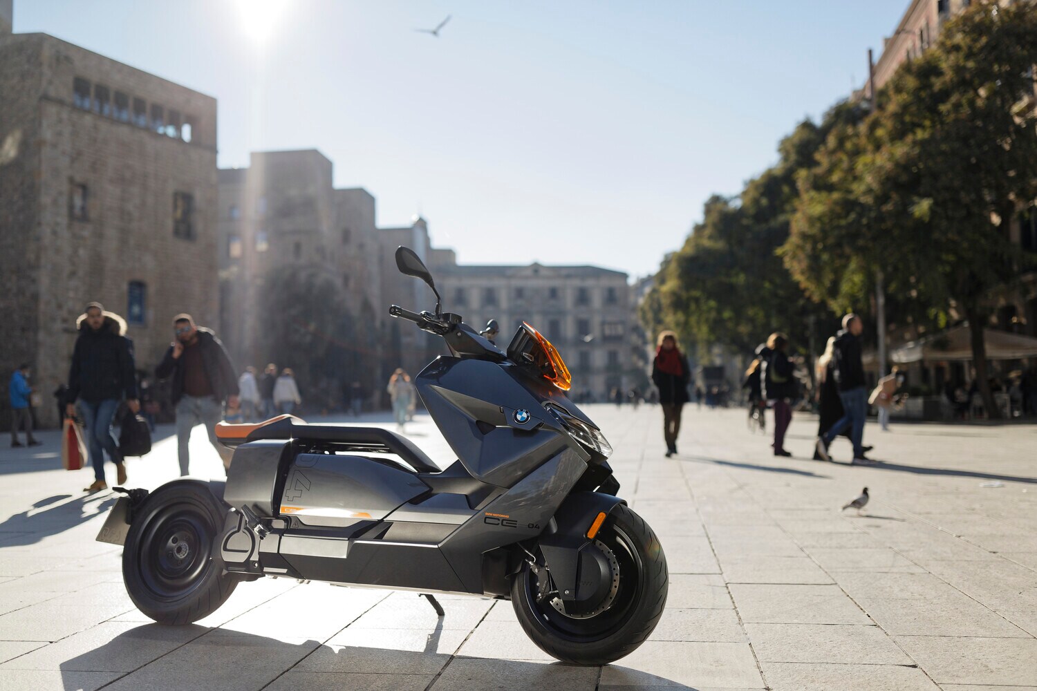 Ein grauer BMW CE 04 parkt vor Palmen in einem Fußgängerbereich.