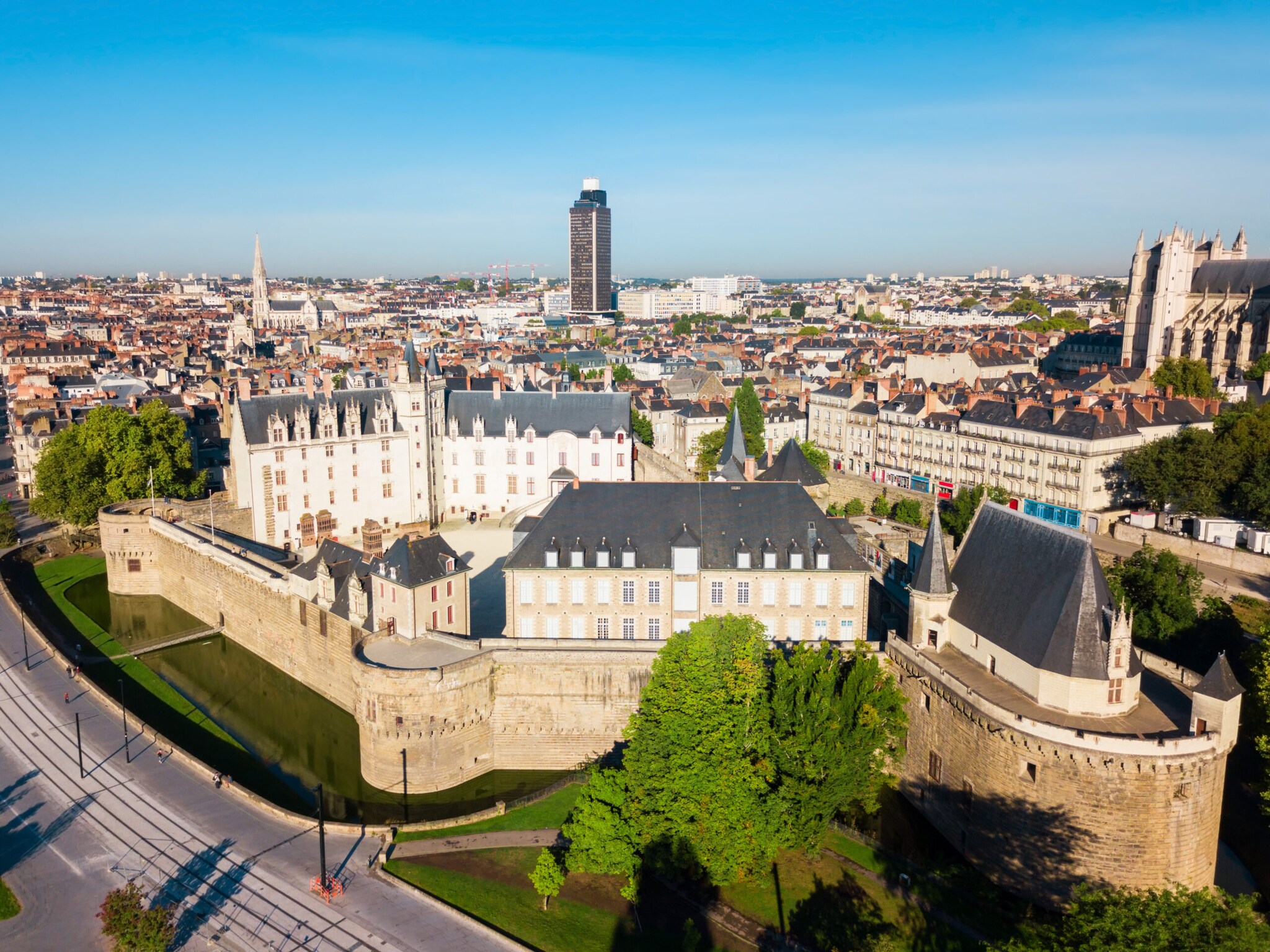 Blick auf ein von einer Mauer umgebenes Schloss vor einer Stadtsilhouette Blick auf ein von einer Mauer umgebenes Schloss vor einer Stadtsilhouette