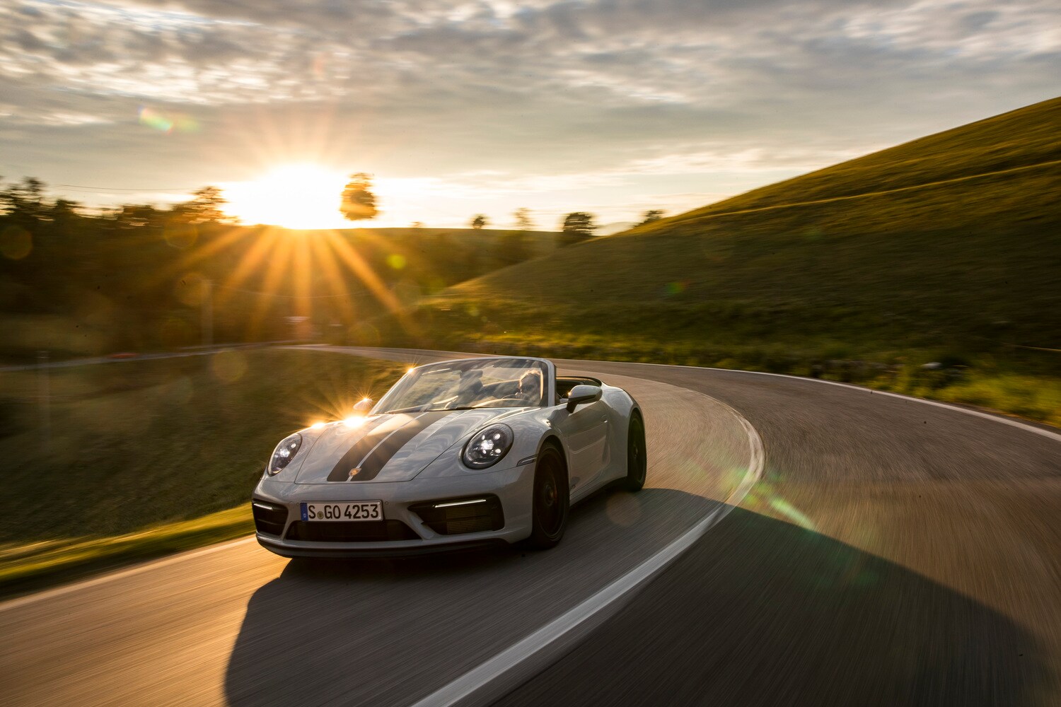 Ein graues Cabriolet fährt durch eine Kurve. Ein graues Cabriolet fährt durch eine Kurve.