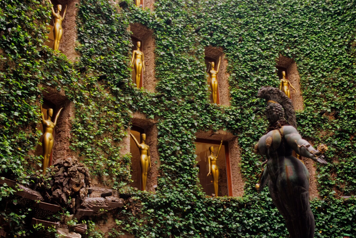 Goldene Skulpturen in Fenstern in einem begrünten Innenhof