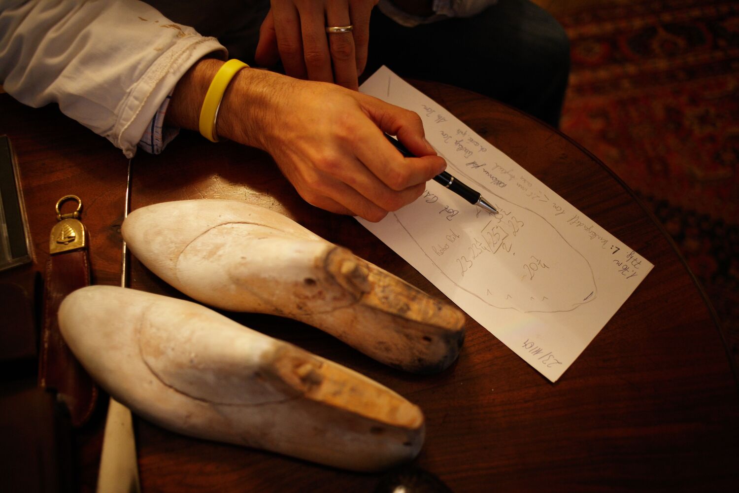 Zwei Modelle für maßgefertigte Schuhe neben einer Zeichnung mit Maßen.