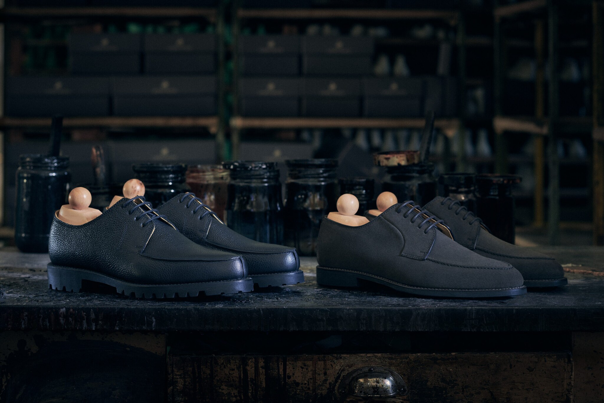 Zwei Paar schwarze Herrenschuhe mit Schuhspannern aus Holz.