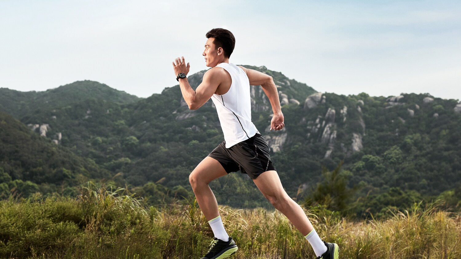 Mann joggt im Sportdress, im Hintergrund ein bewaldeter Berg Mann joggt im Sportdress, im Hintergrund ein bewaldeter Berg