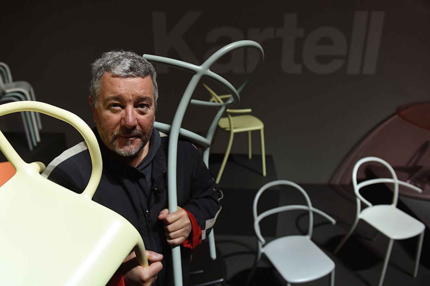 Designer Philippe Starck hält zwei Stühle