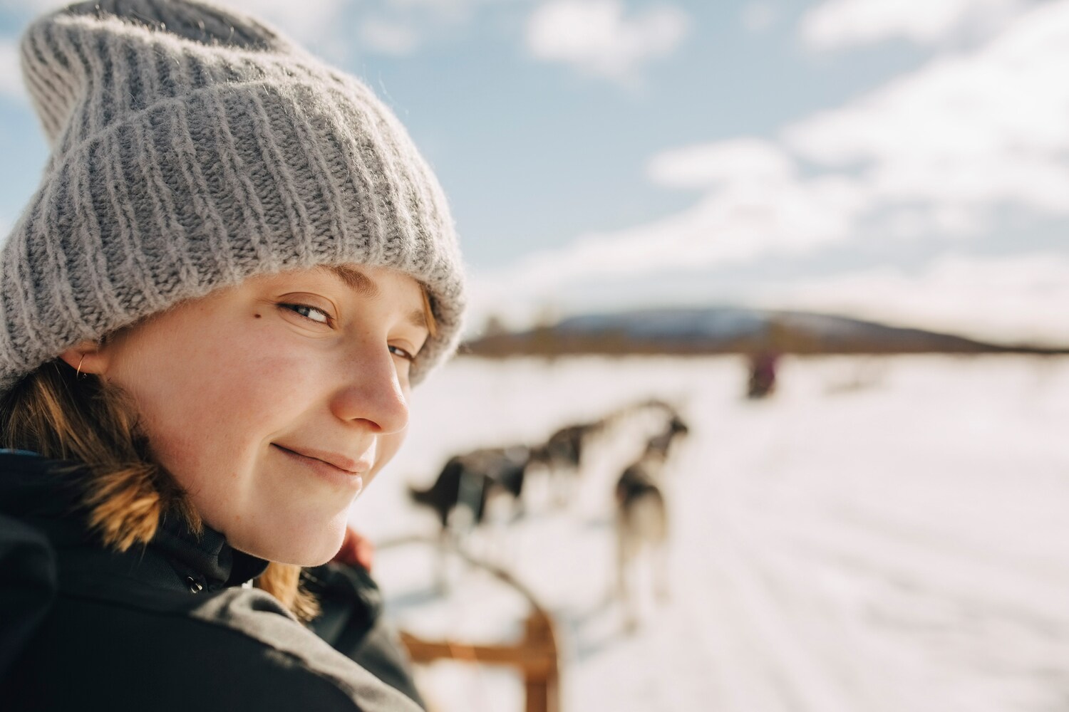 Eine junge Frau vor einem Hundeschlitten.