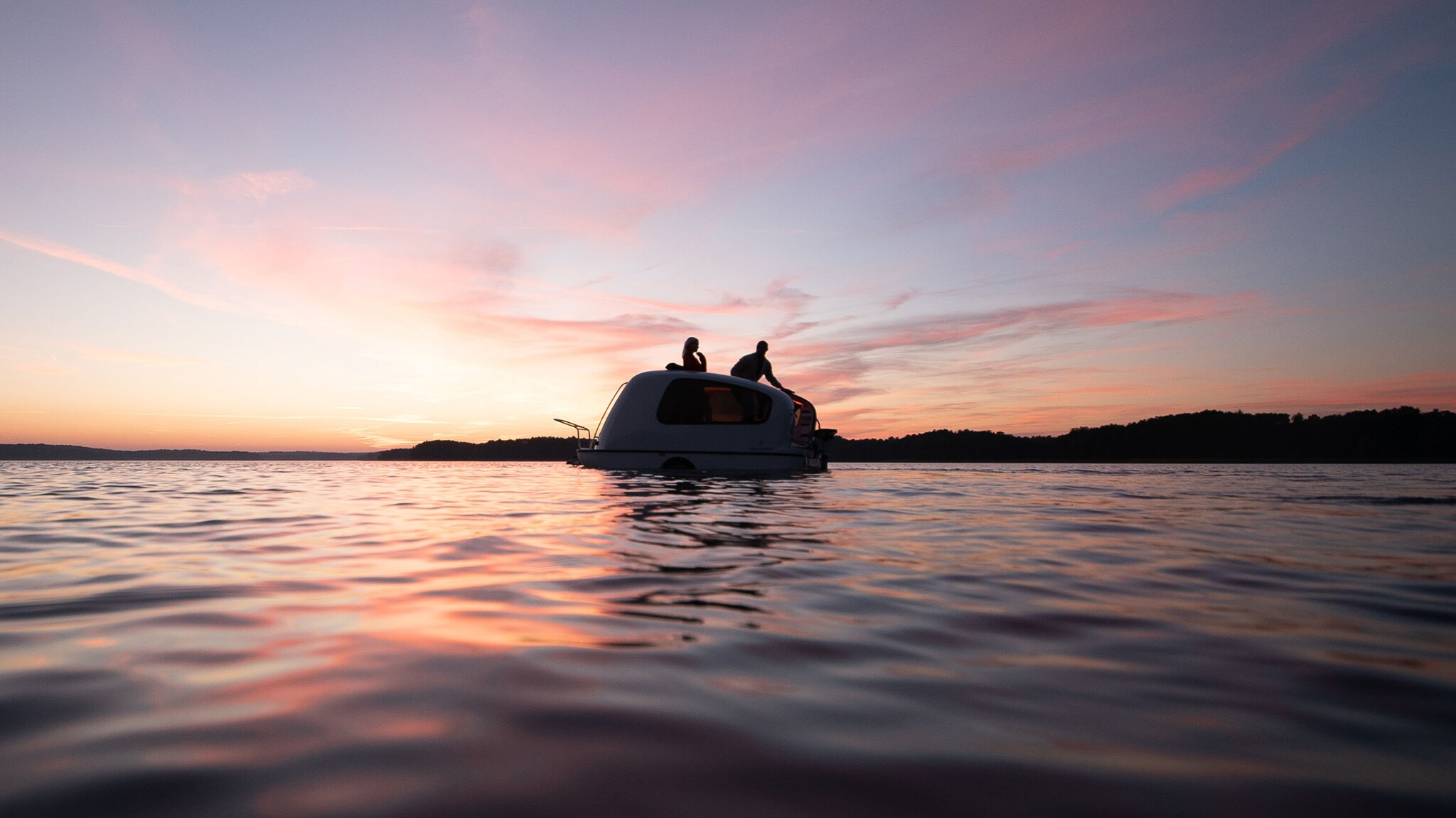 Ein Paar bei Sonnenuntergang auf dem Dach eines Schwimmwohnwagens