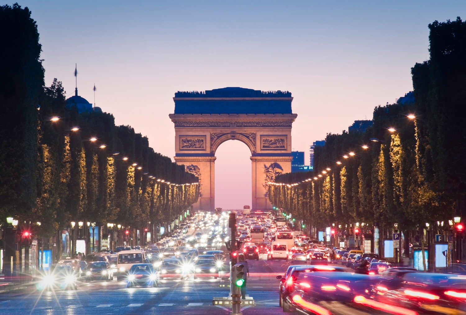 Reger Autoverkehr vor dem beleuchteten Arc de Triomphe in Paris am Abend. Reger Autoverkehr vor dem beleuchteten Arc de Triomphe in Paris am Abend.