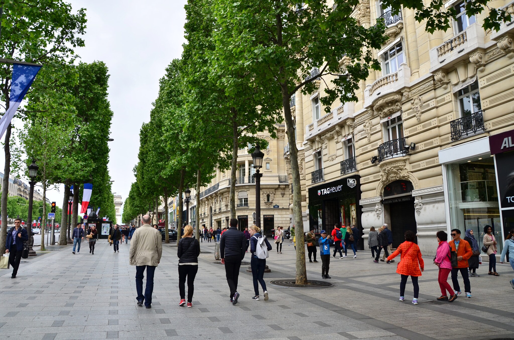 Mehrere Menschen flanieren über die Einkaufsstraße Champs-Élysées.