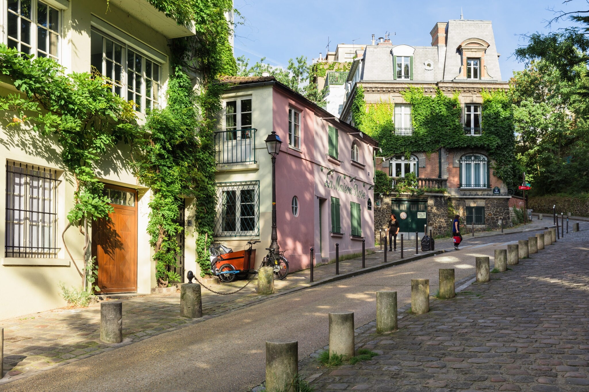 Steile Straße neben historischen, mit Pflanzen berankten Häusern auf dem Montmartre Hügel. Steile Straße neben historischen, mit Pflanzen berankten Häusern auf dem Montmartre Hügel.