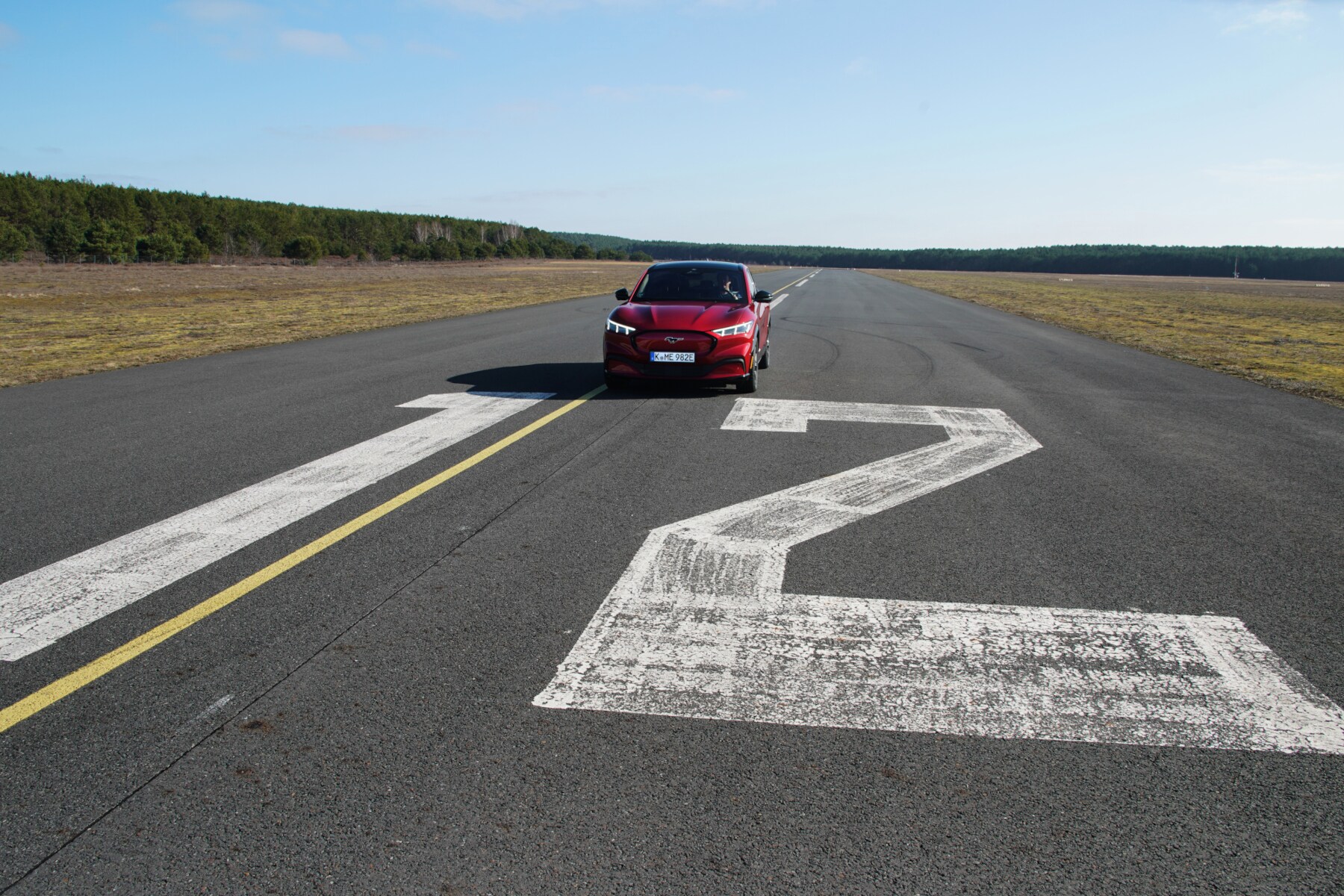 Ein roter Ford Mustang Mach-E auf einem Flughafenrollfeld