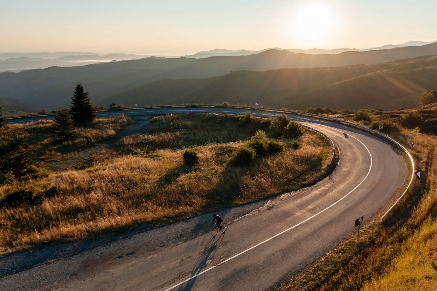 Ein Radfahrer auf einer einsamen Straße im Sonnenuntergang. Ein Radfahrer auf einer einsamen Straße im Sonnenuntergang.