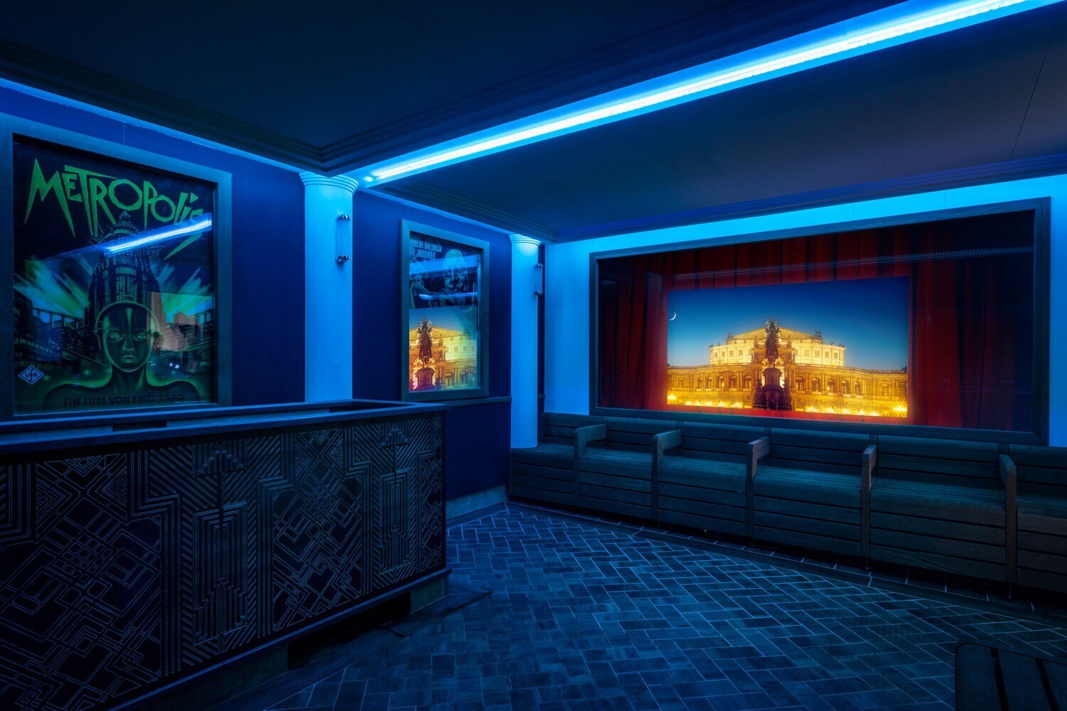 Blau beleuchtete Sauna im Stil eines Kinos mit Leinwand und Filmplakaten an der Wand Blau beleuchtete Sauna im Stil eines Kinos mit Leinwand und Filmplakaten an der Wand