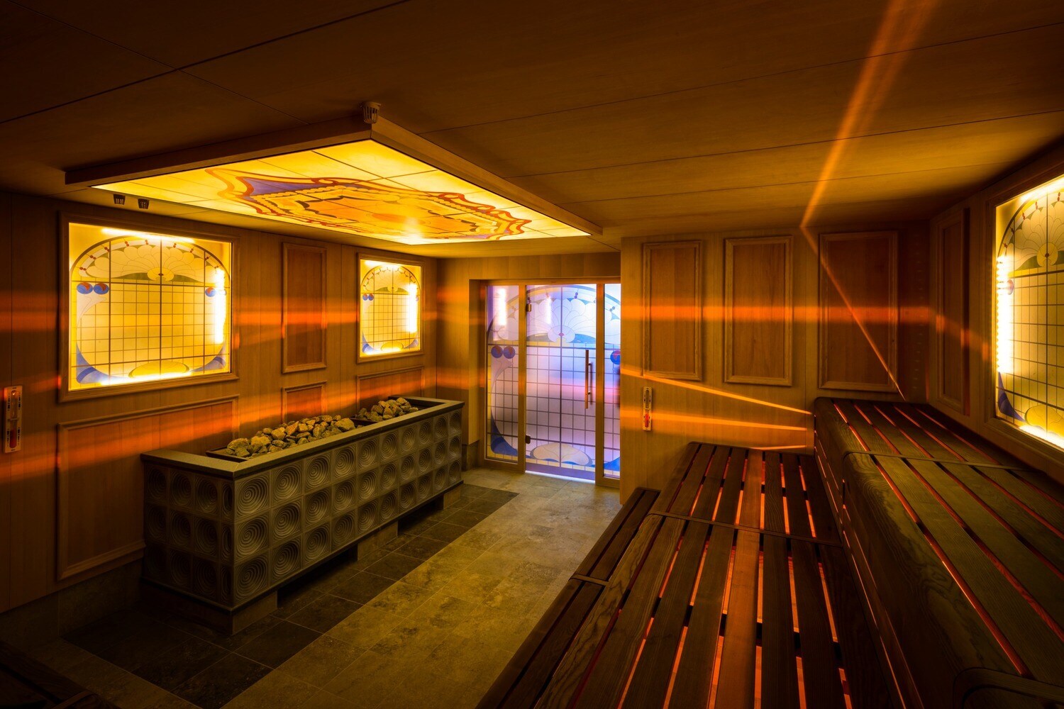 Holzsauna mit gelben, dekorierten Glasplatten, durch die Lichtstrahlen ins Innere dringen Holzsauna mit gelben, dekorierten Glasplatten, durch die Lichtstrahlen ins Innere dringen