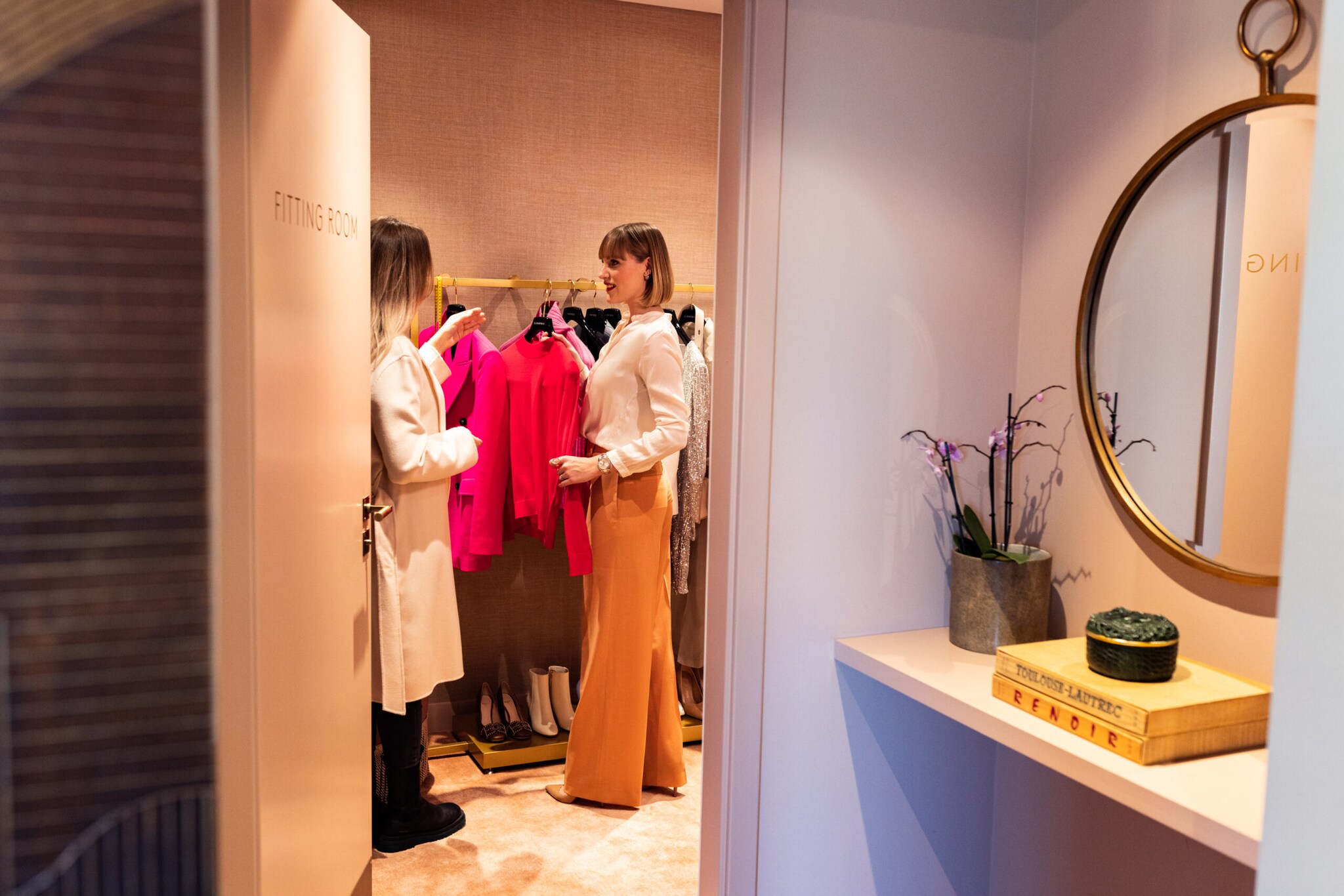 Eine Personal Shopperin präsentiert ihrer Kundin eine Auswahl an Outfits.