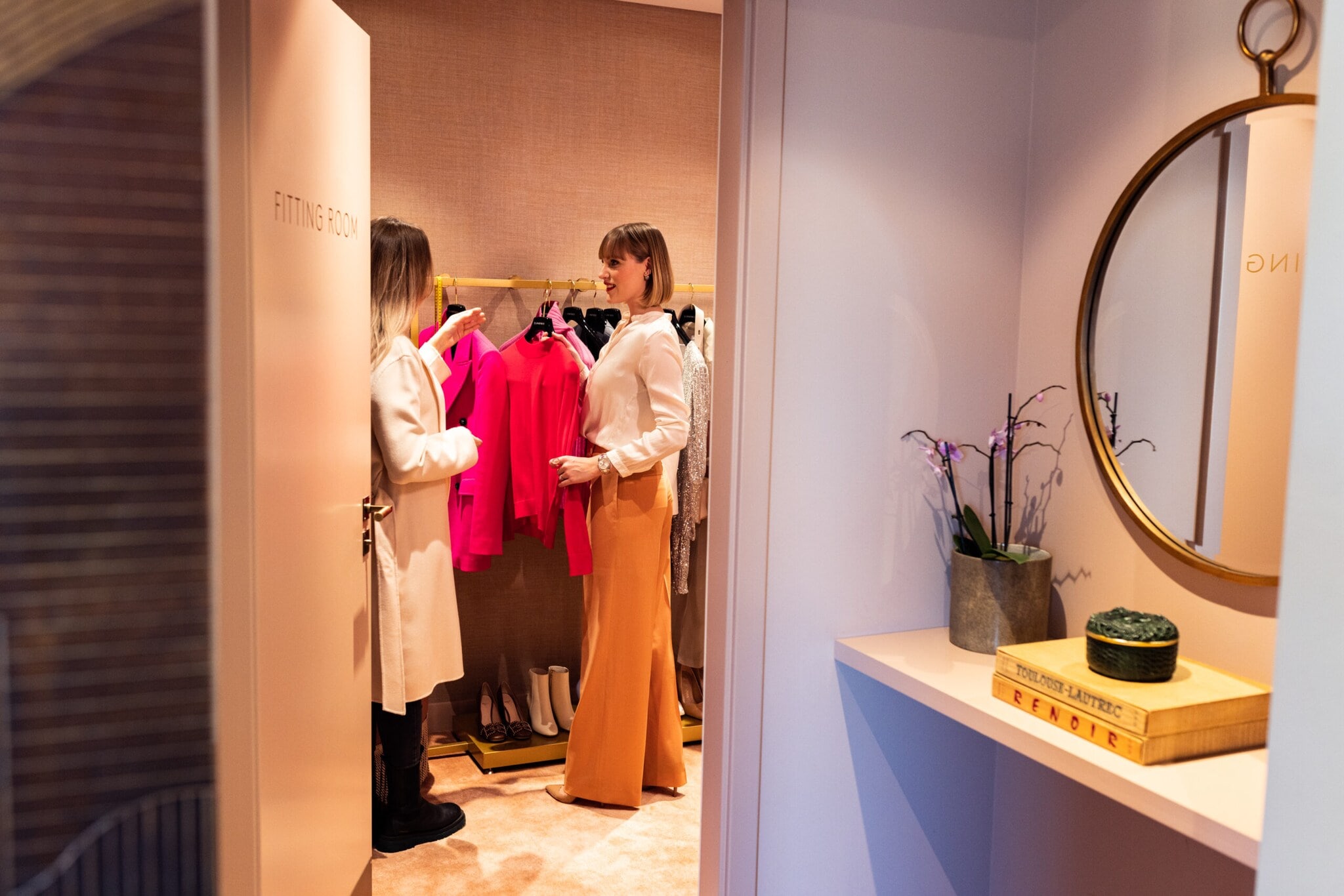 Eine Personal Shopperin präsentiert ihrer Kundin eine Auswahl an Outfits. Eine Personal Shopperin präsentiert ihrer Kundin eine Auswahl an Outfits.