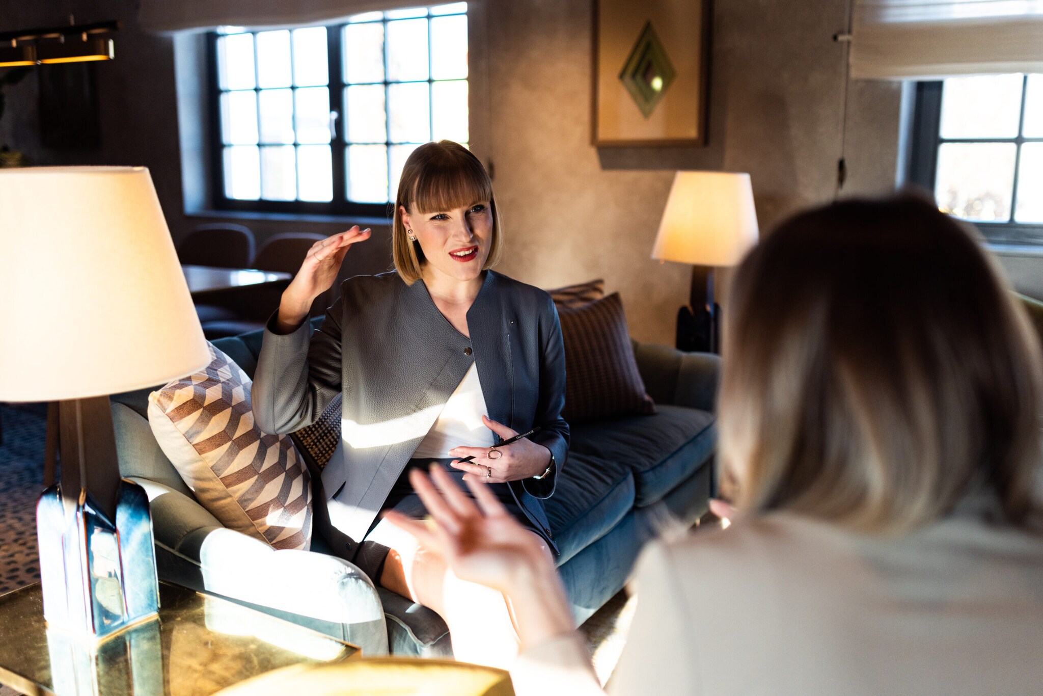 Eine Personal Shopperin sitzt ihrer Kundin gegenüber und ist im Gespräch vertieft.