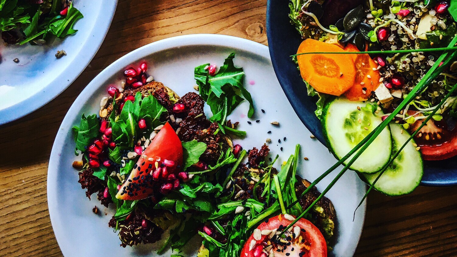 Angerichtete Speisen mit frischer Tomate und Gurke auf Tellern.