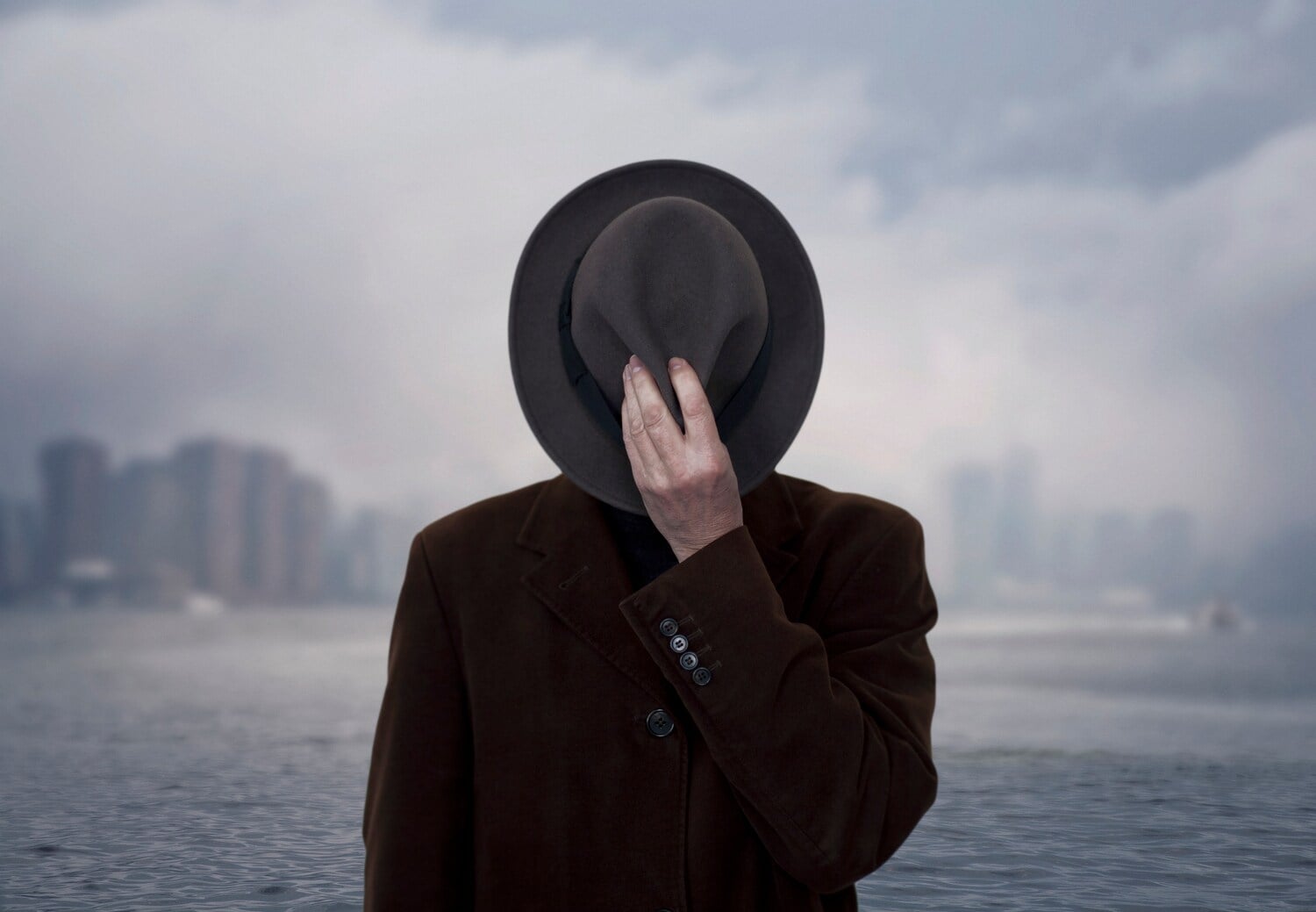 Ein Schwarz-Weiß-Bild einer Person, die sich einen Hut vor das Gesicht hält Ein Schwarz-Weiß-Bild einer Person, die sich einen Hut vor das Gesicht hält