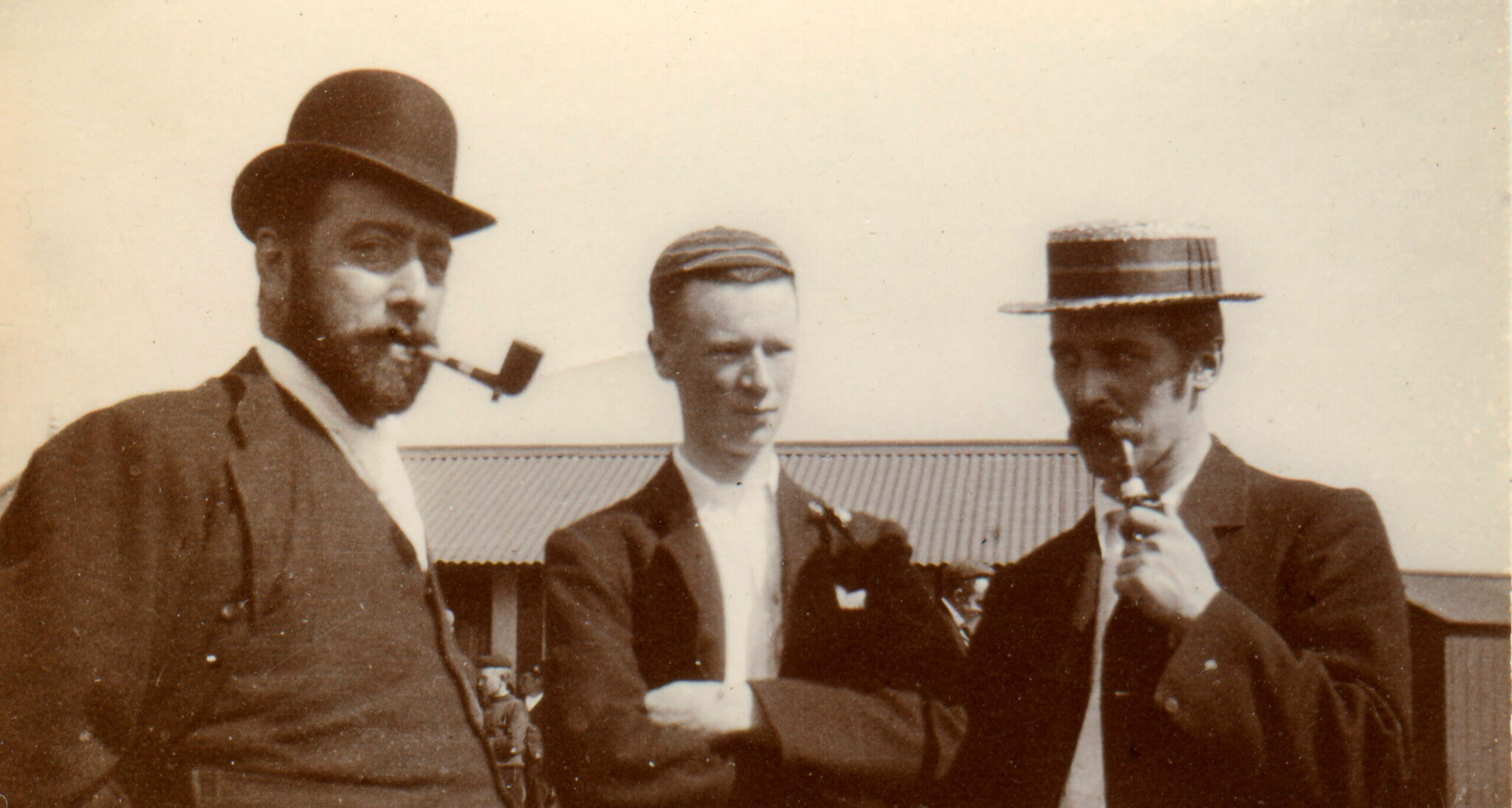 Ein historisches Foto dreier Männer, zwei tragen Hüte und rauchen Pfeife Ein historisches Foto dreier Männer, zwei tragen Hüte und rauchen Pfeife