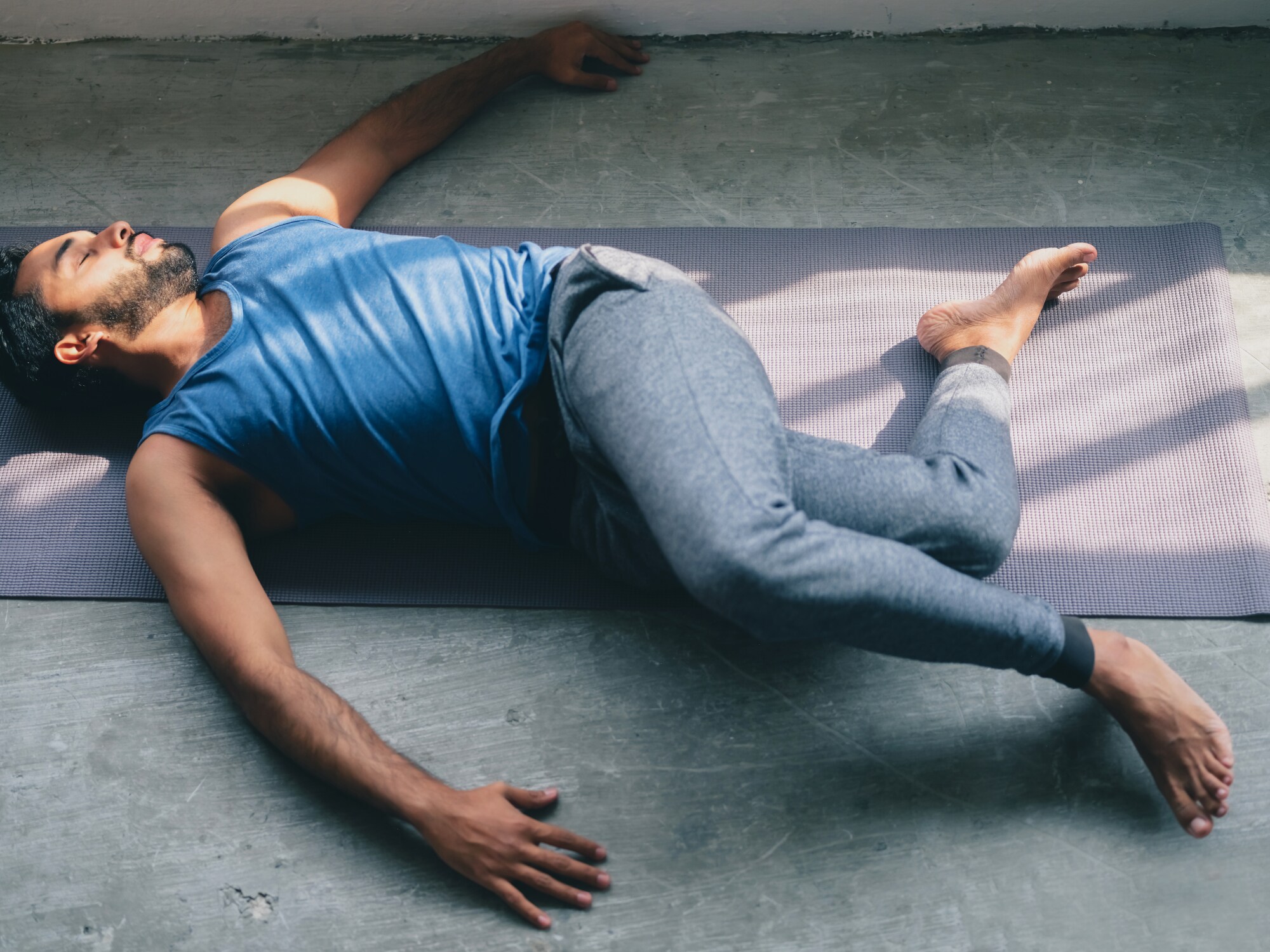 Mann liegt in einer Drehdehnung auf der Matte Mann liegt in einer Drehdehnung auf der Matte