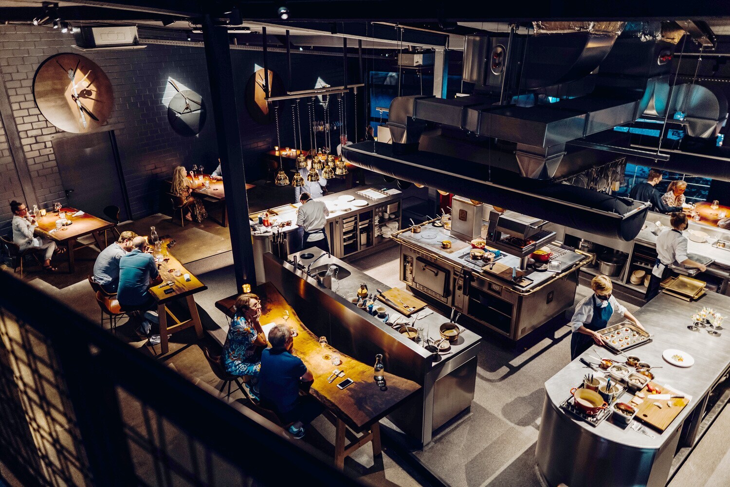 Blick in ein Restaurant mit Holztischen und mittiger Kücheninsel