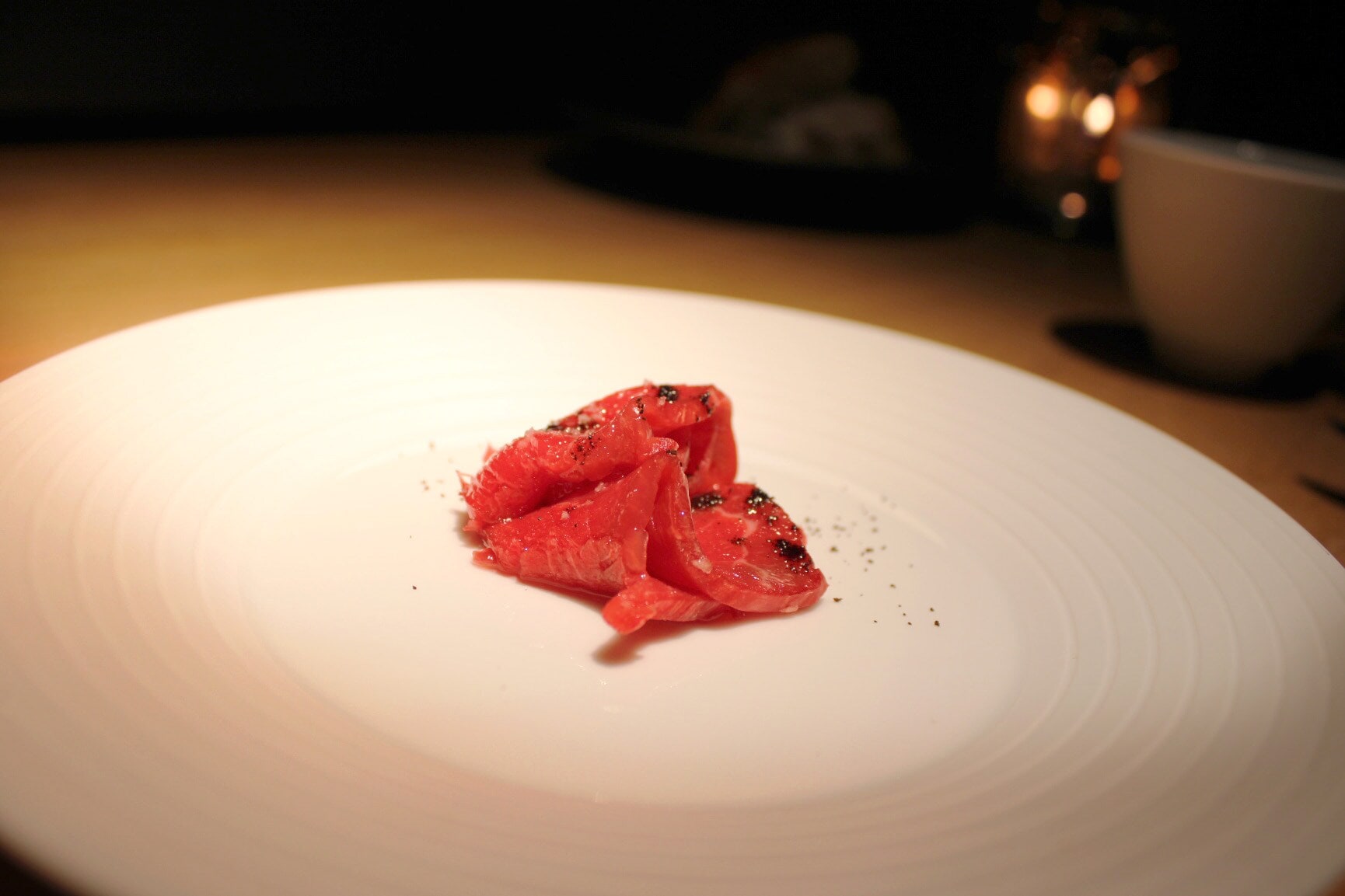 Dünne, mit gemahlenem Kaffee bestreute Rinderscheibchen auf einem weißen Teller Dünne, mit gemahlenem Kaffee bestreute Rinderscheibchen auf einem weißen Teller