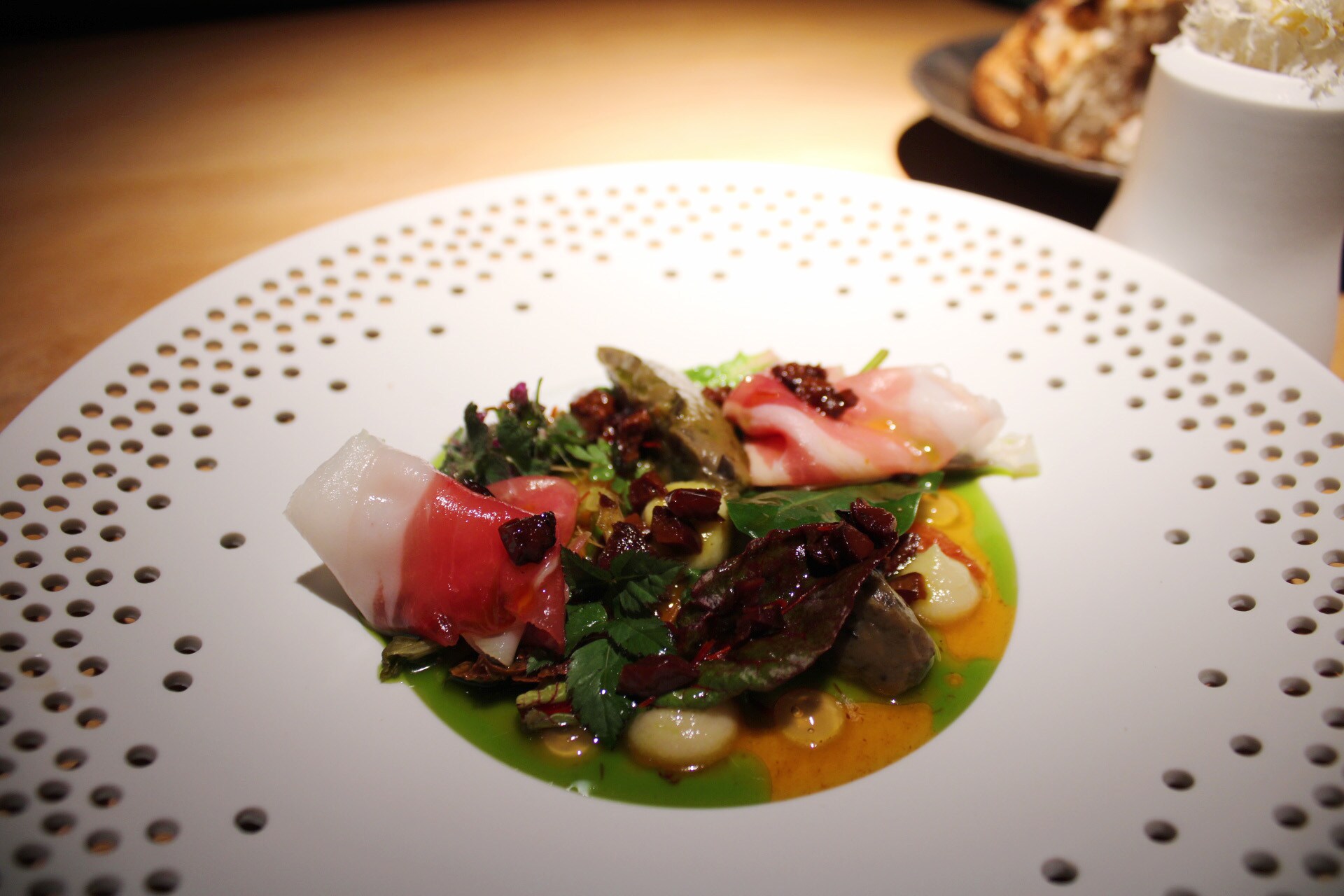 Ein Teller mit bunt angerichtetem Salat mit zwei gerollten Schinkenscheiben
