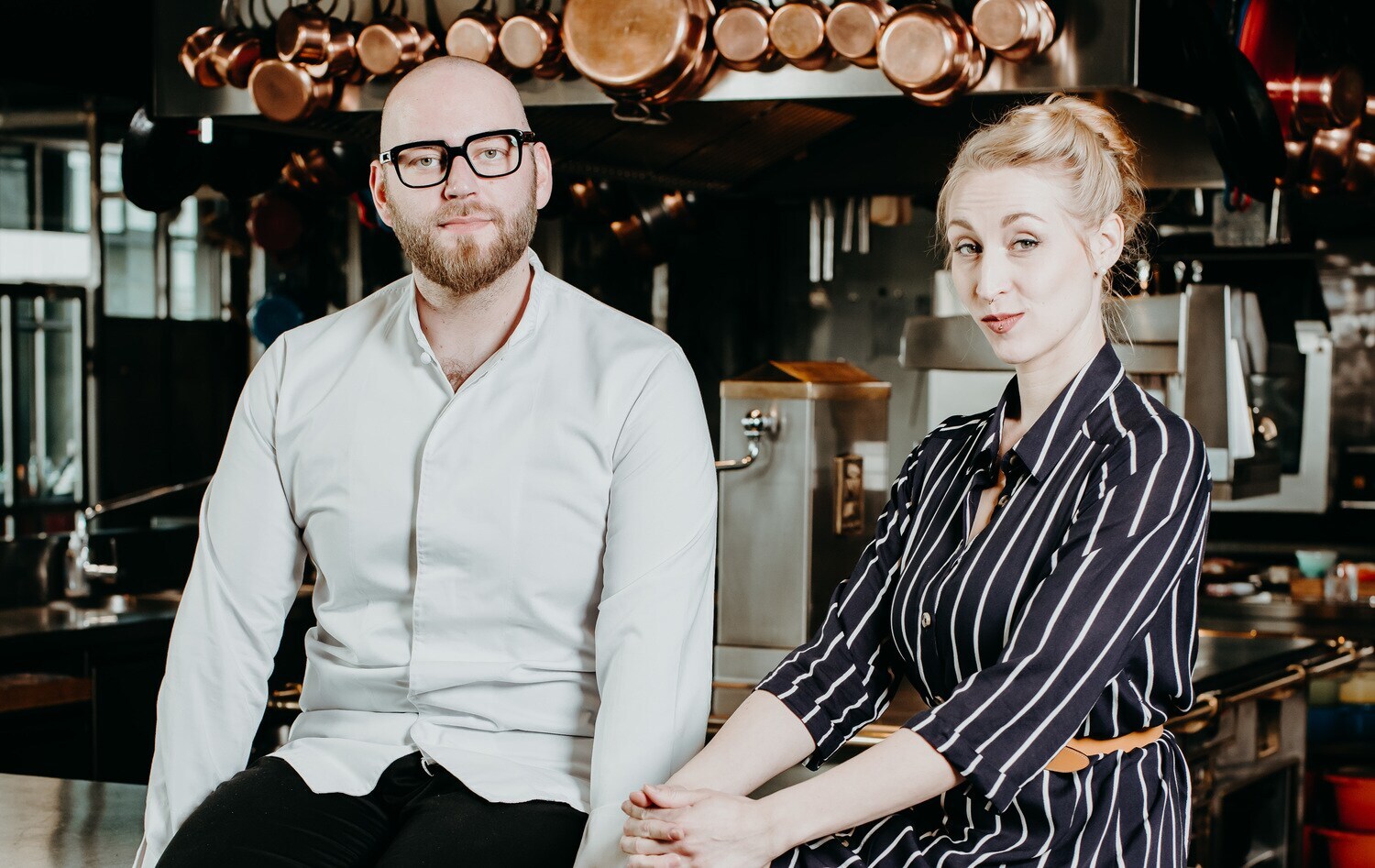 Ein Mann und eine Frau sitzen auf einem Tresen vor einer Küche