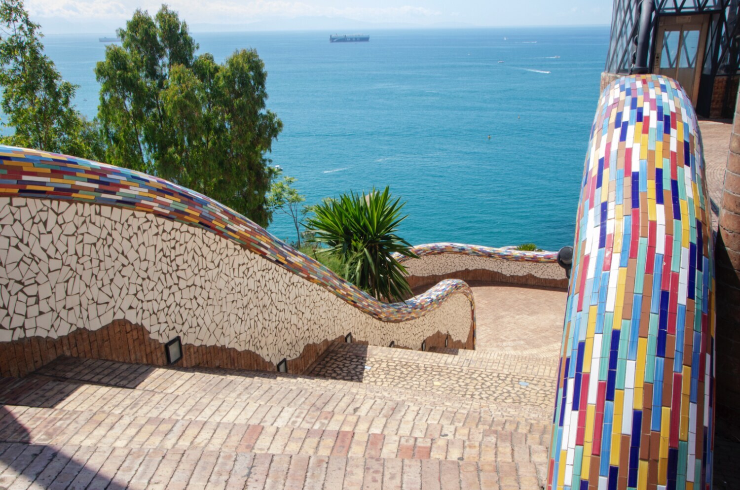 Sonniger Weg mit Keramikfliesen zum Meer.