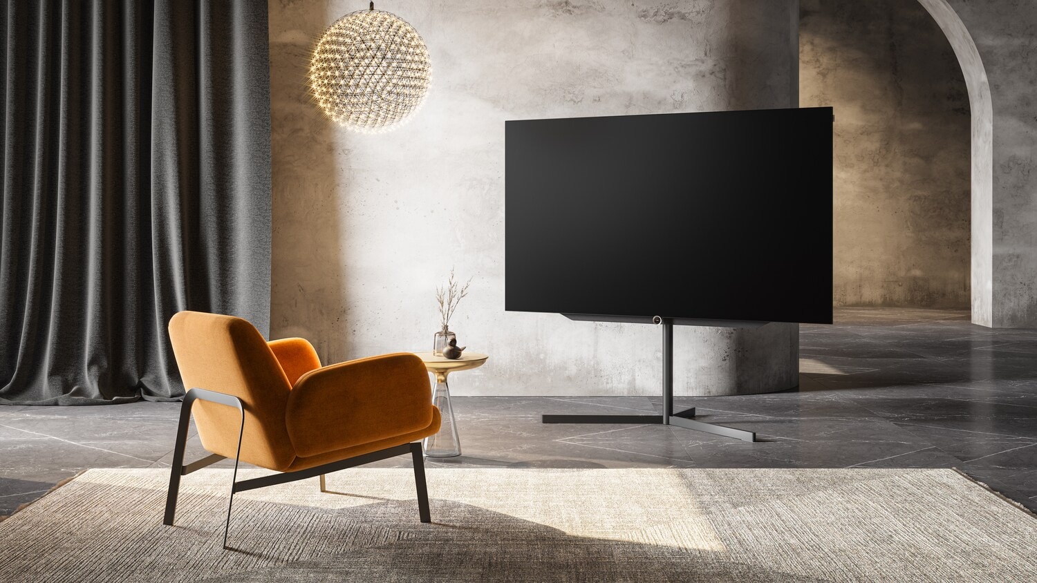 Der Fernseher Loewe bild s.77 in einem Wohnzimmer mit einem Stuhl davor Der Fernseher Loewe bild s.77 in einem Wohnzimmer mit einem Stuhl davor